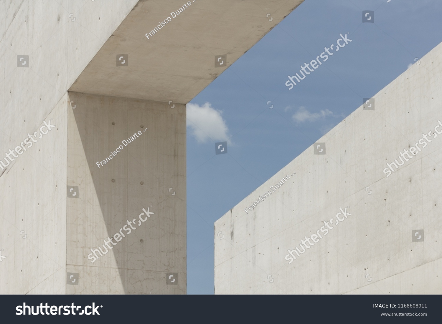 Architectural photography. Geometric composition with two large and strong cement blocks. building against the blue sky with white clouds. Modern structures architecture. Minimalist design fragments. #2168608911