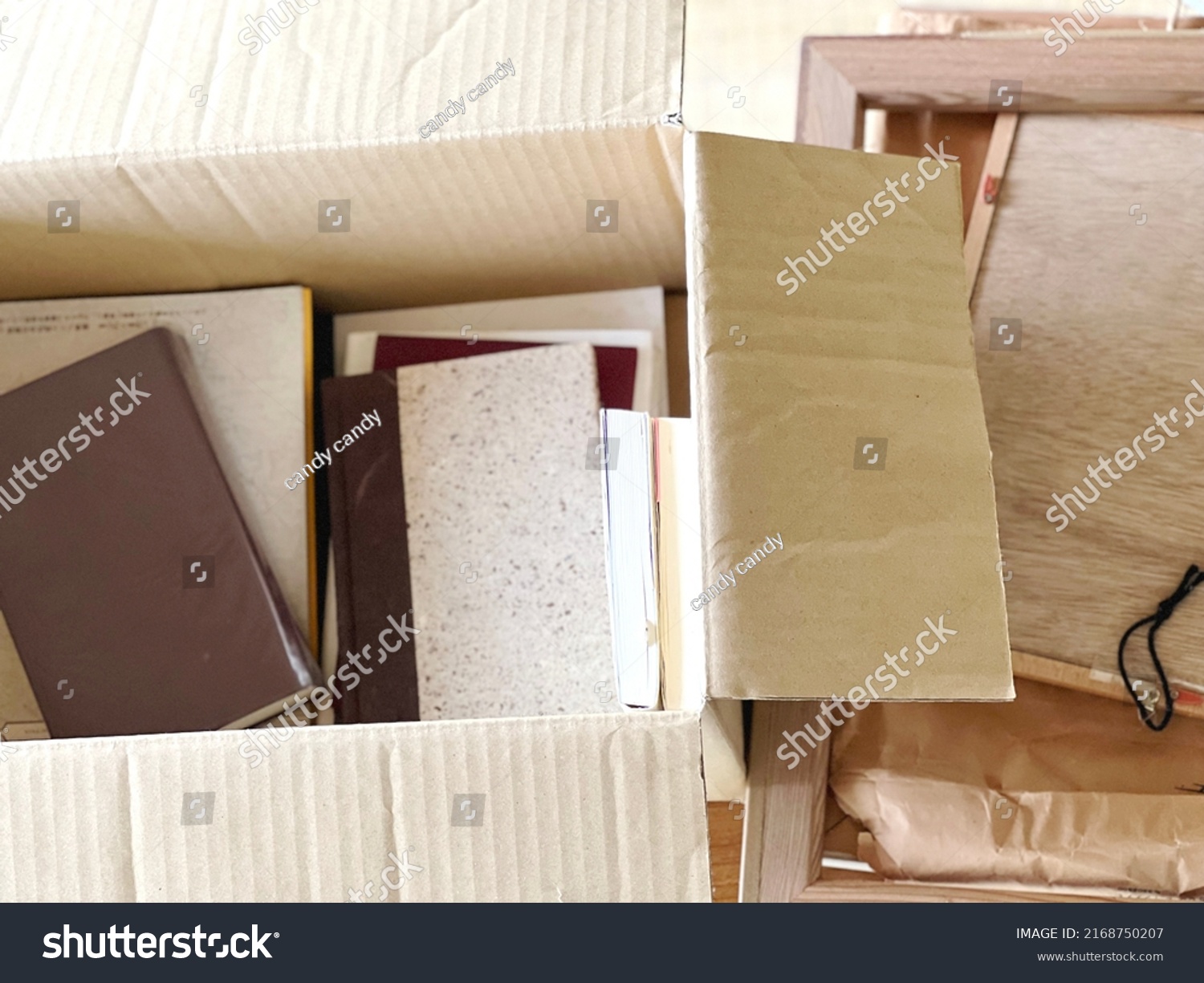 Books and frames in a cardboard box in bird's-eye view #2168750207