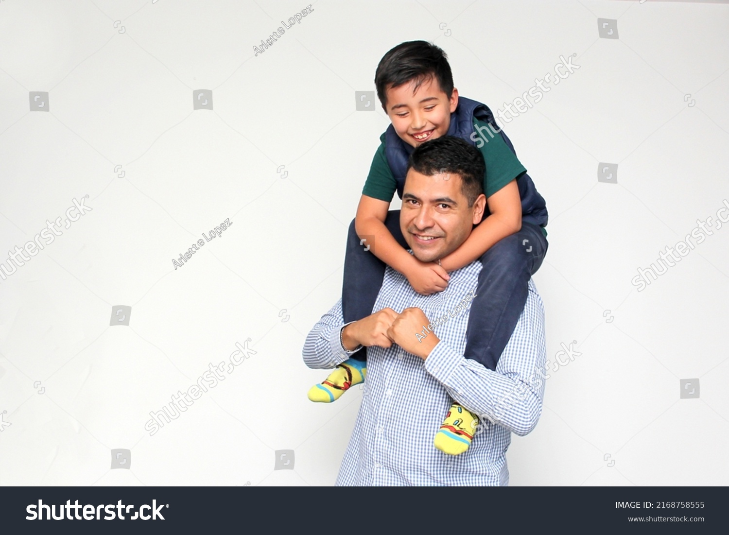 Single dark-haired dad Latino and hispanic son play and have fun together spending quality family time on Father's Day celebrating victory with hugs and kisses
 #2168758555