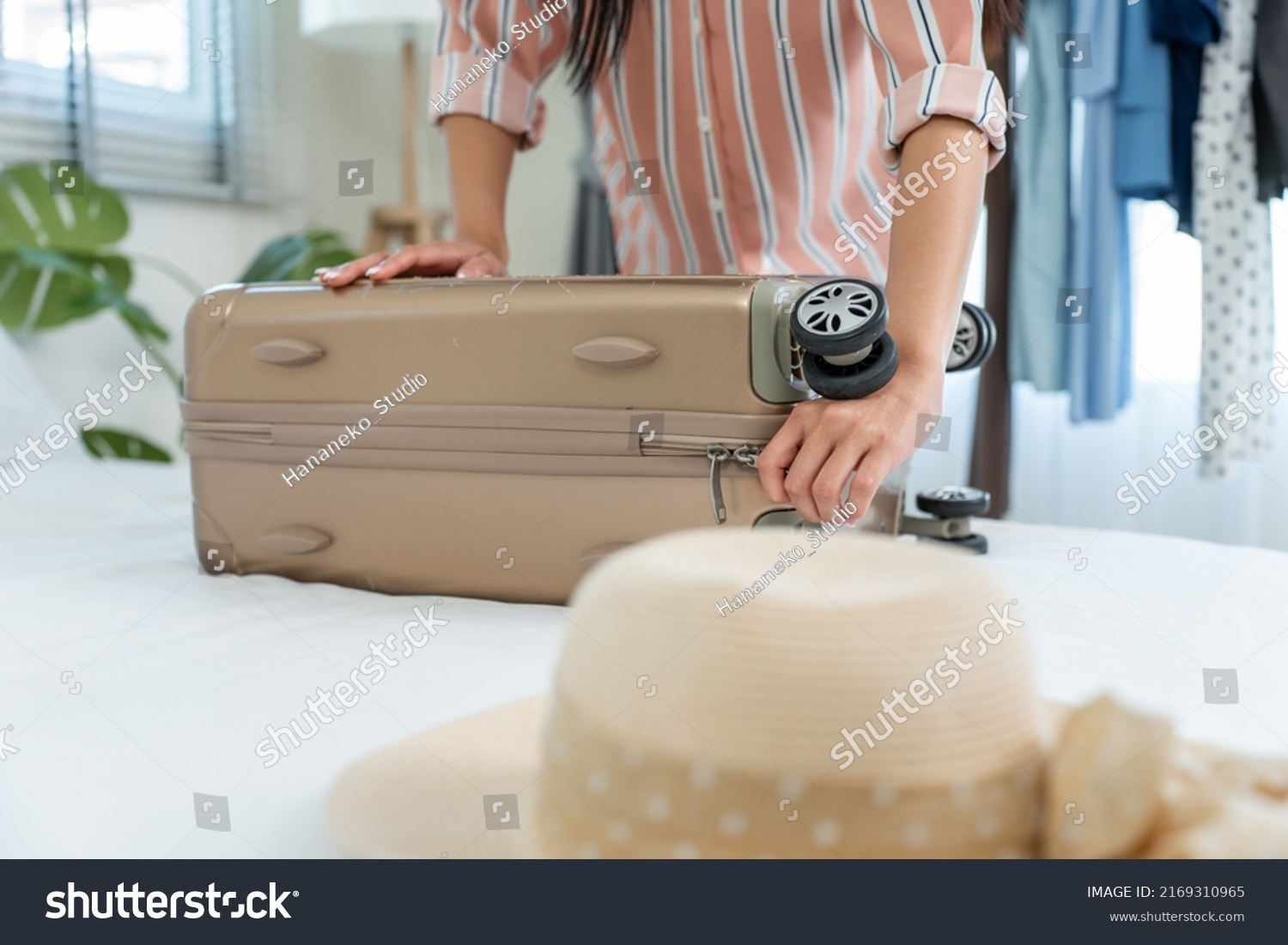 Close up hands of young woman preparing clothes and packing a suitcase. Attractive female tourist traveler feel happy and relax while preparing luggage on bed, ready to travel on holiday vacation trip #2169310965