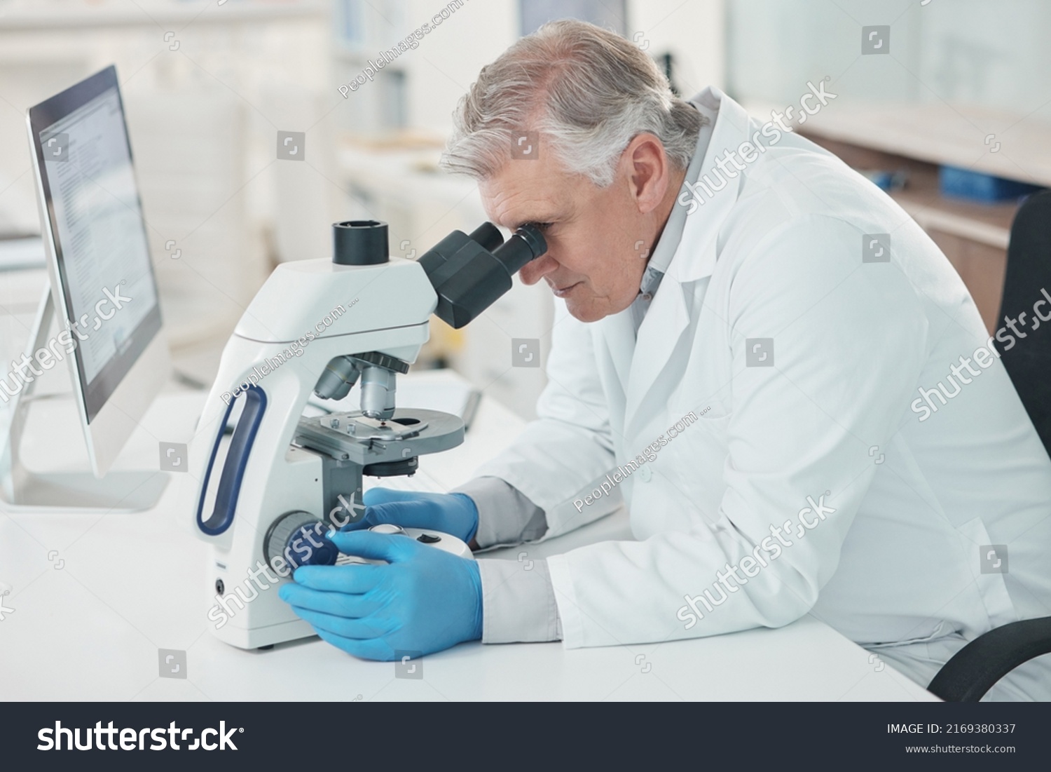 Theres a lot to take note of when magnified. Shot of a mature scientist using a microscope in a lab. #2169380337