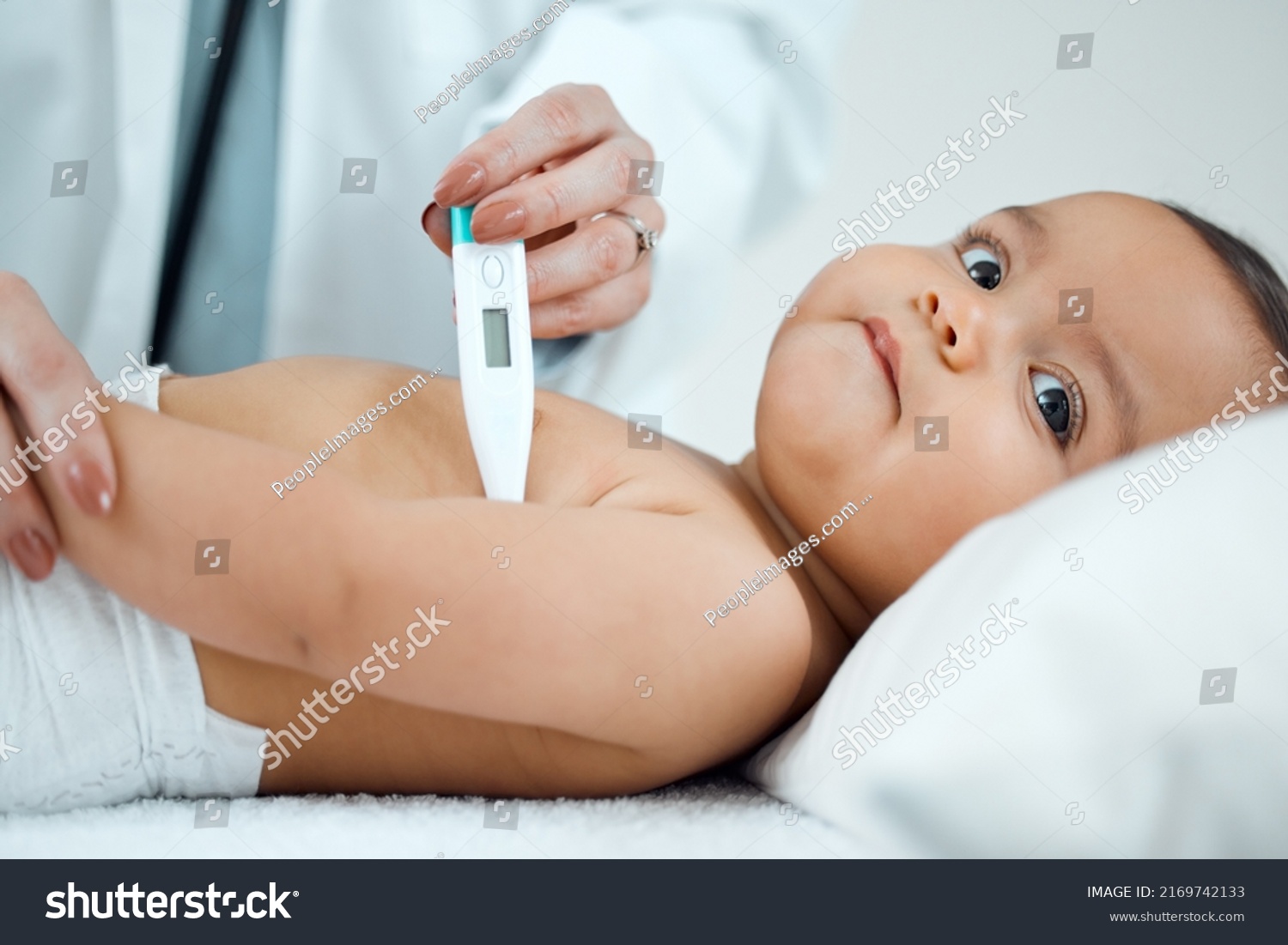 Lets start by taking your temperature. Shot of a paediatrician taking a babys temperature with a thermometer in a clinic. #2169742133