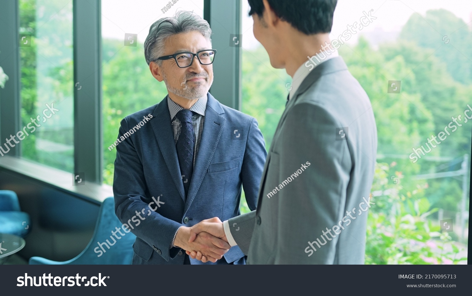 Middle aged executive man and young businessperson shaking hands in the office. #2170095713