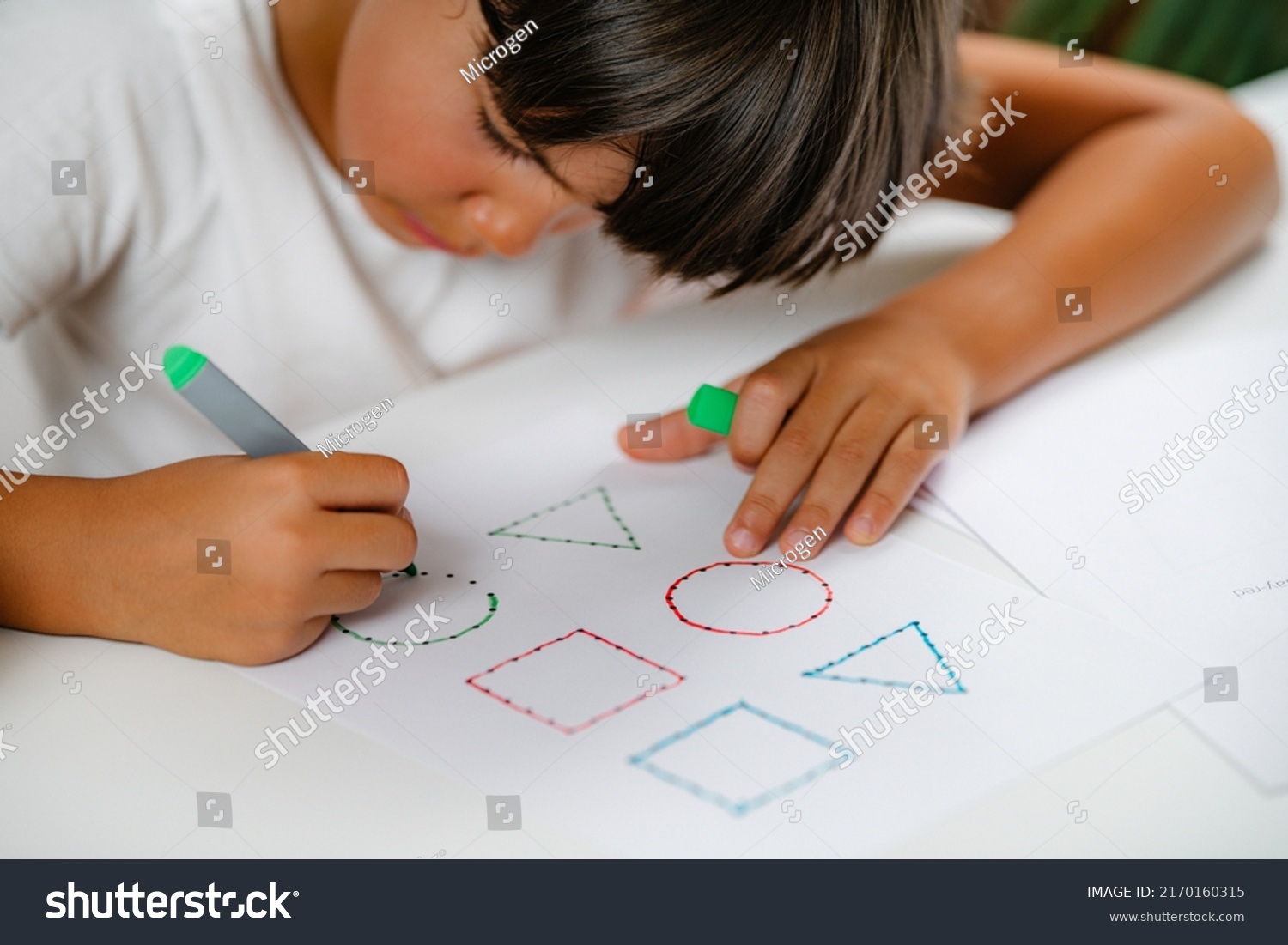 Preschooler boy sitting at the desk, drawing shapes  #2170160315
