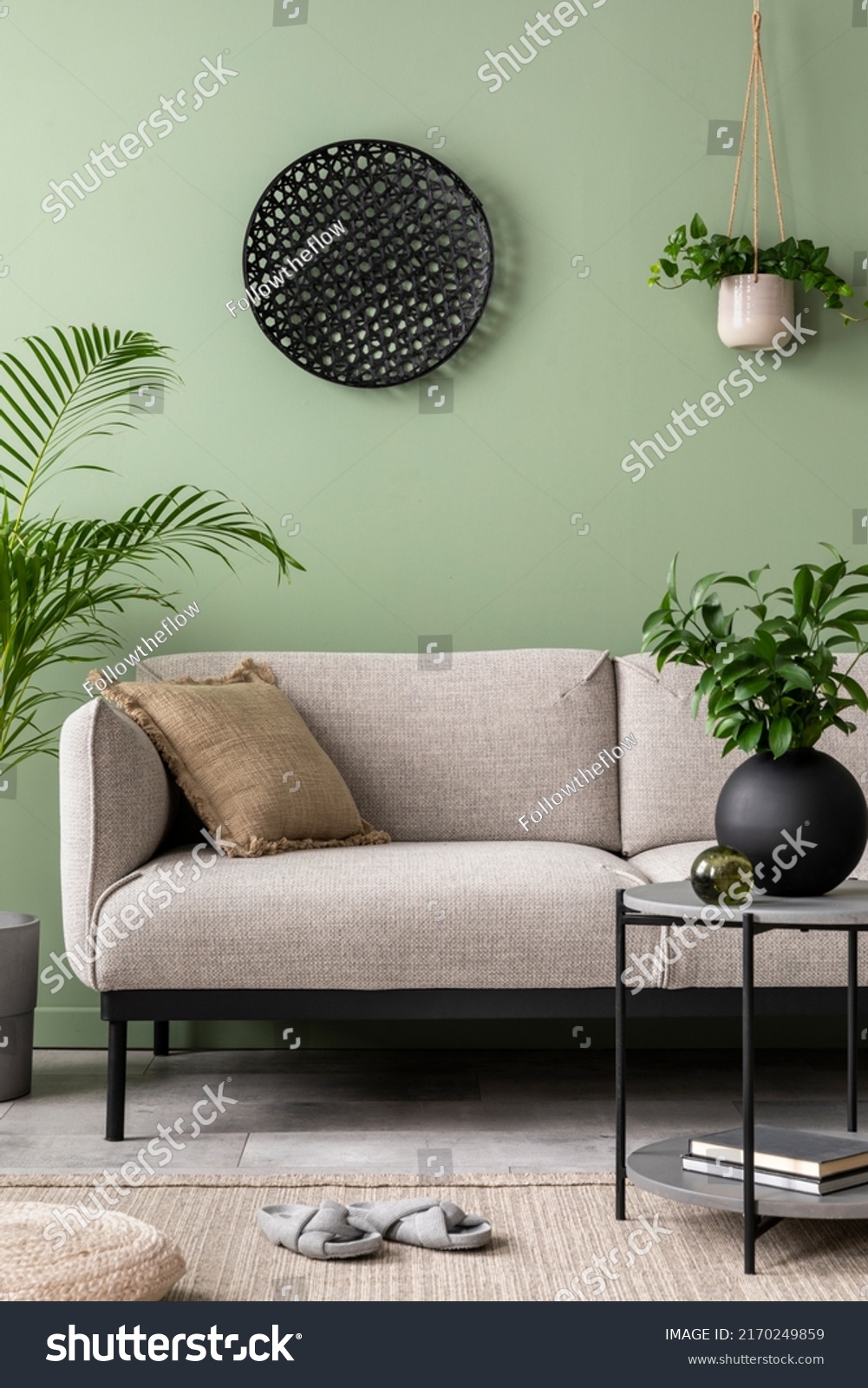 The stylish composition at living room interior with green wall, design gray sofa, coffee table, dark ornament and elegant personal accessories. Beige pillow. Cozy apartment. Template. 
 #2170249859