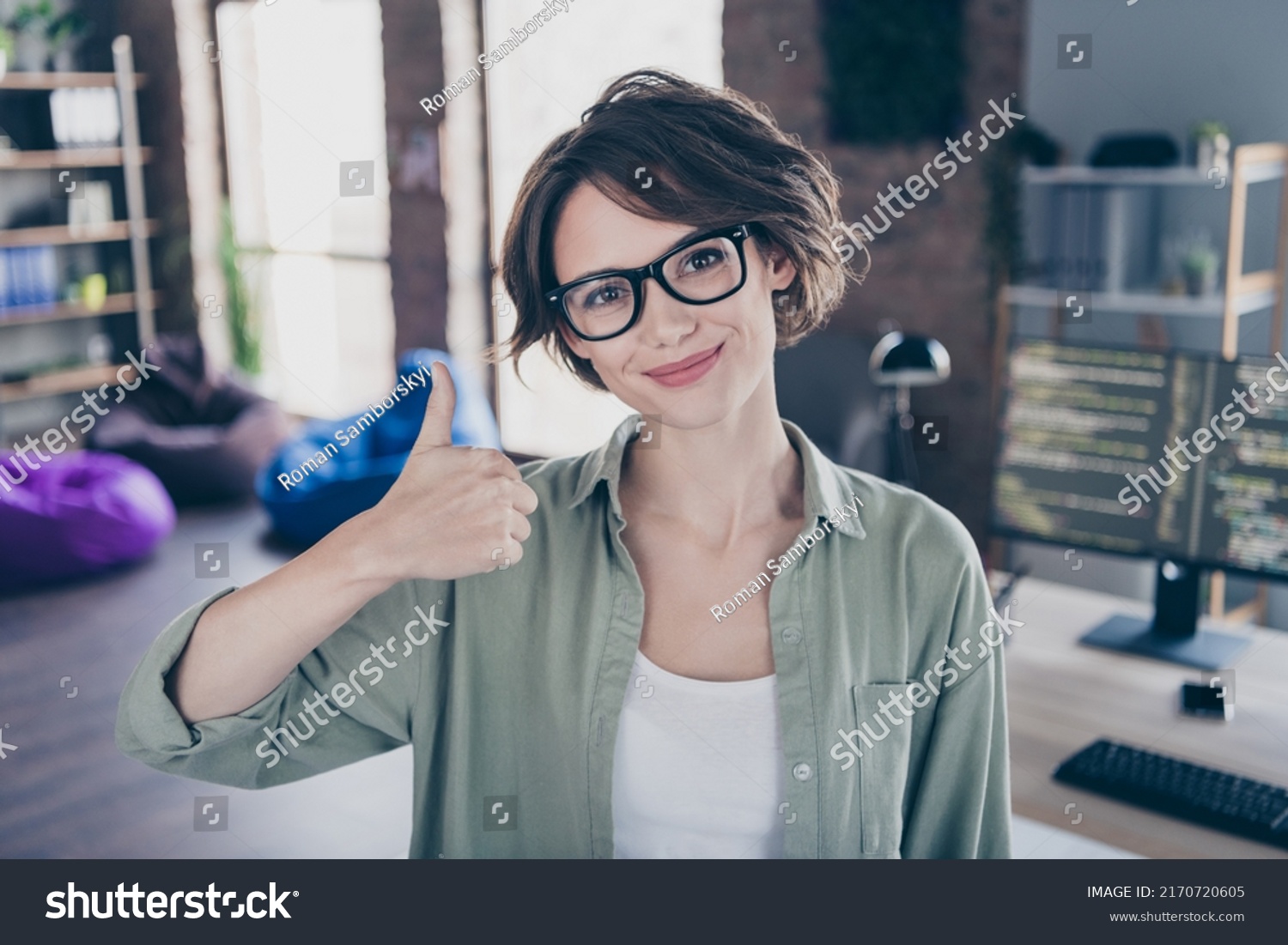 Photo of happy web designer look camera show thumb up approve feedback rate loft room workplace #2170720605