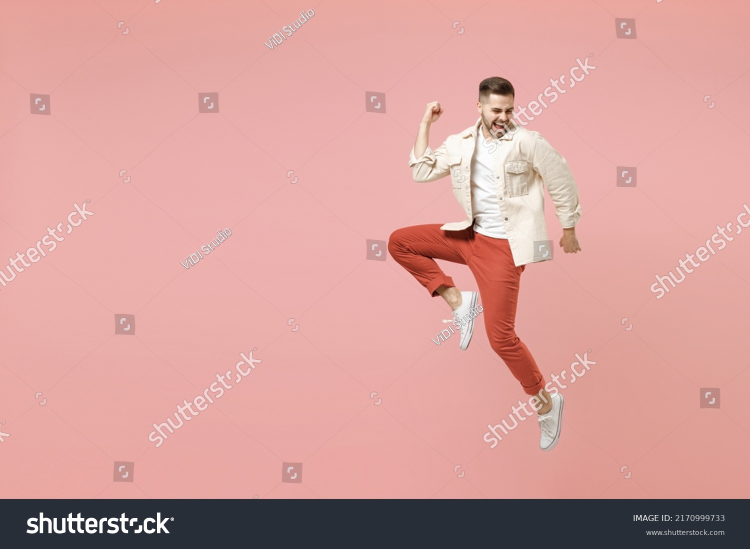 Full length young happy overjoyed fun trendy fashionable caucasian man 20s in jacket white t-shirt jump do winner gesture clench fist celebrating isolated on pastel pink background studio portrait. #2170999733