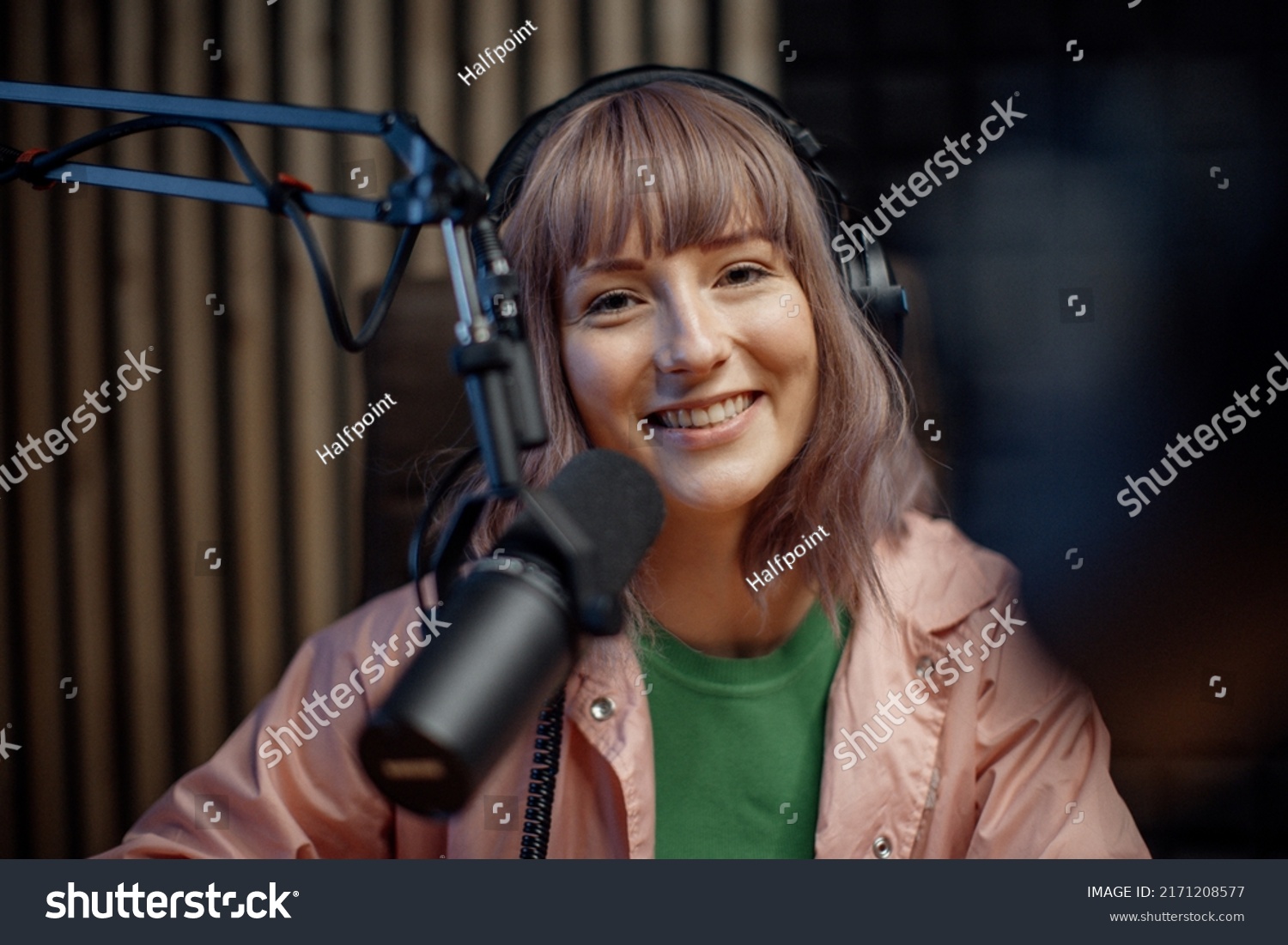 Portrait of female radio host speaking in microphone while moderating a live show #2171208577
