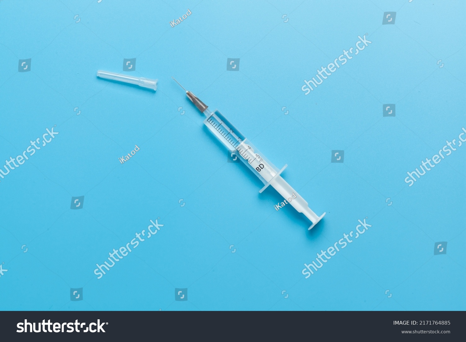 Medical syringe for liquid 5 ml. White medical syringe with a cap, isolated on a blue background. #2171764885