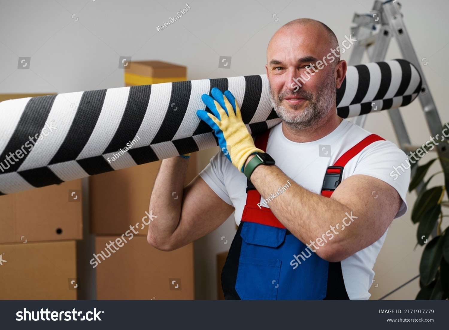Man mover in uniform carrying big rolled carpet for relocation #2171917779