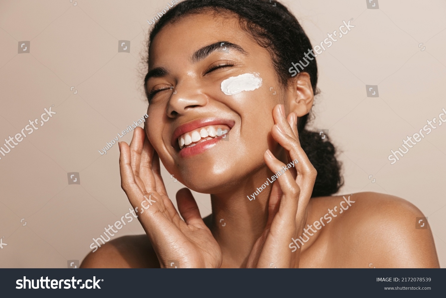 Smiling woman using skincare product. Female taking face cream to apply on facial skin #2172078539