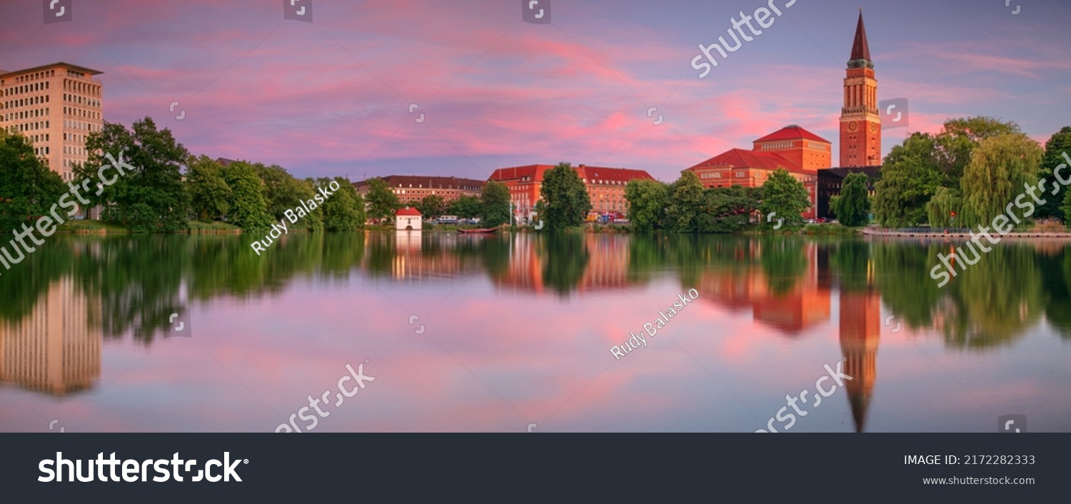 : Kiel, Germany. Panoramic cityscape image of downtown Kiel, Germany with Town Hall, Opera House and reflection of the skyline in Small Kiel at sunset. #2172282333
