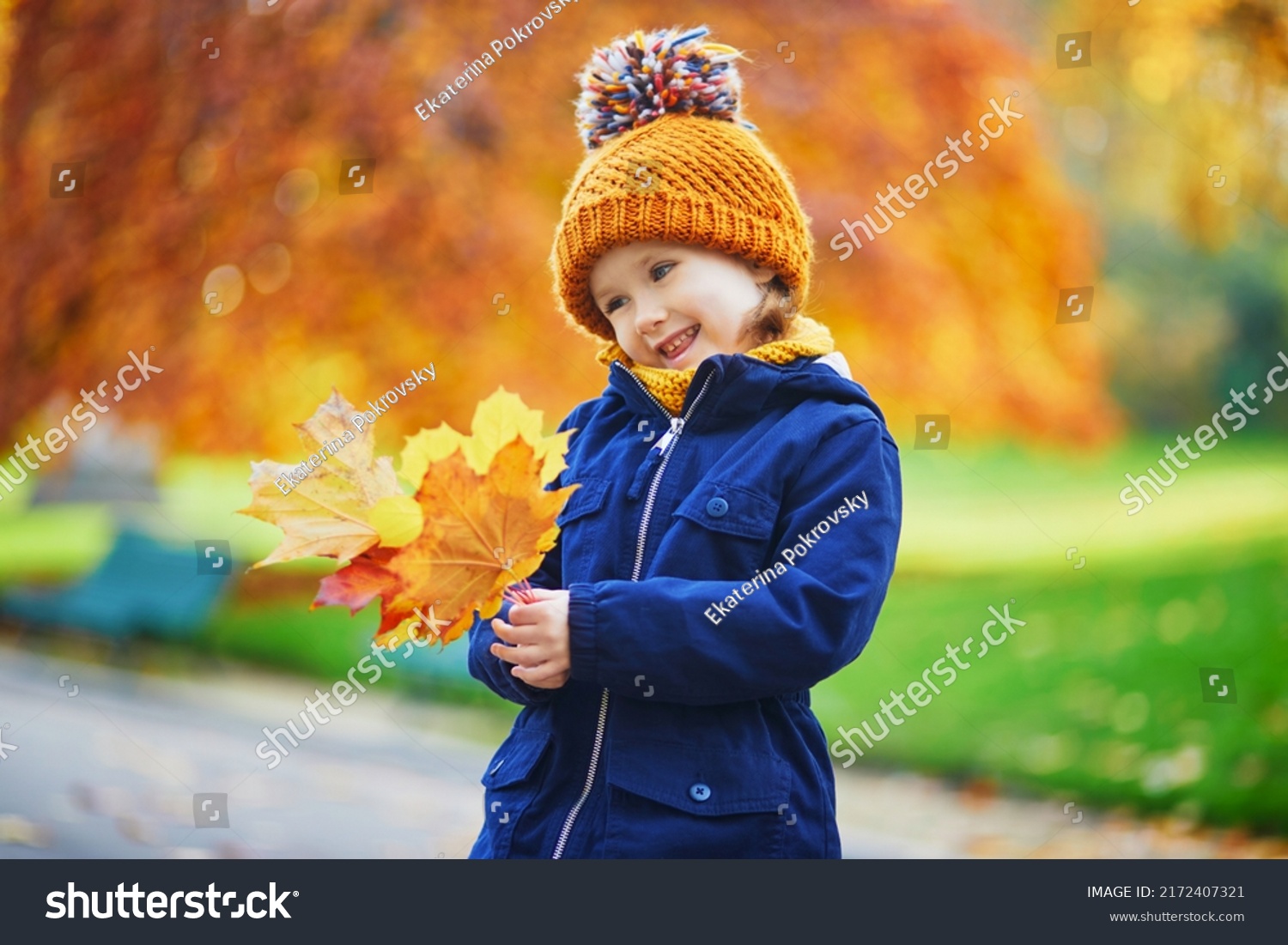 Adorable preschooler girl enjoying nice and sunny autumn day outdoors. Happy child gathering autumn leaves in Paris, France. Outdoor fall activities for kids #2172407321