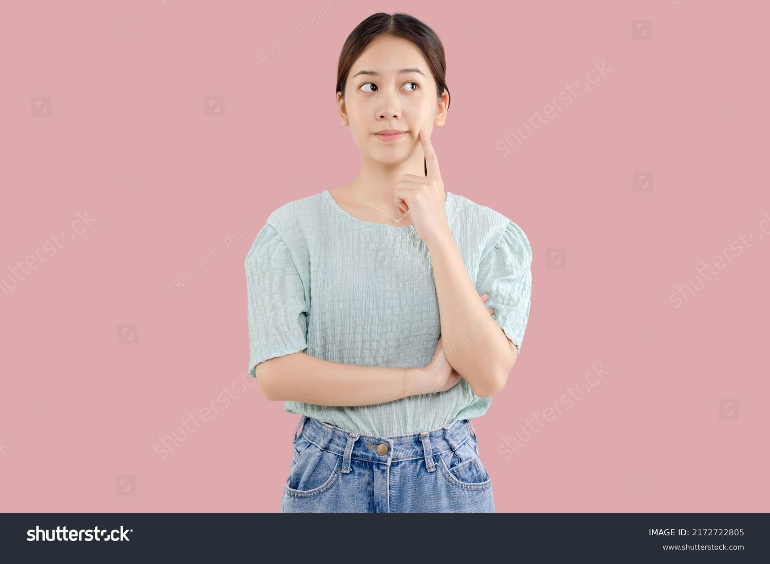 Beautiful young Asian girl thinking and looking upwards. The concept of content thinks about future isolated on pink background. #2172722805