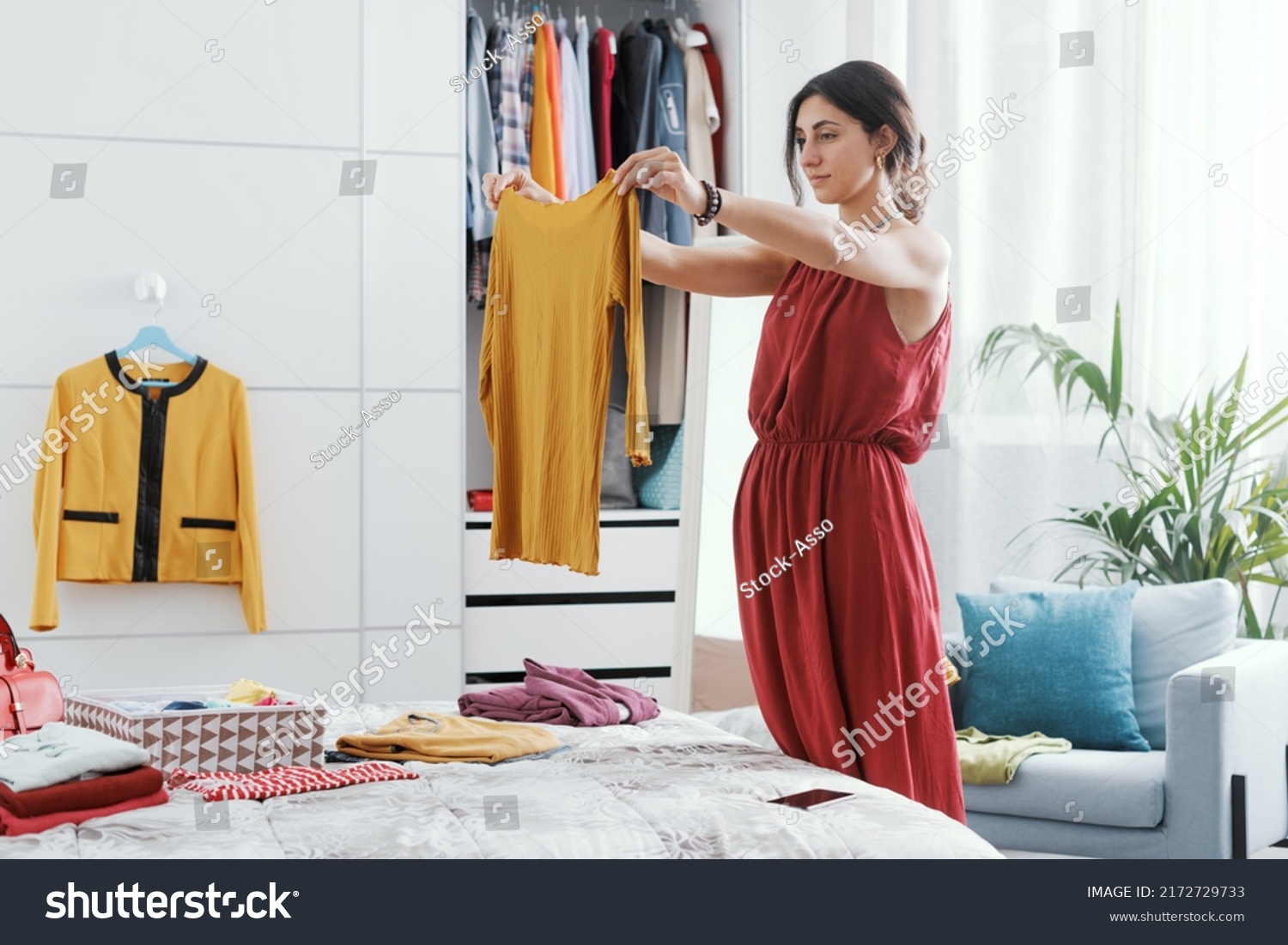 Elegant woman in her bedroom, she is decluttering her wardrobe and choosing clothes #2172729733