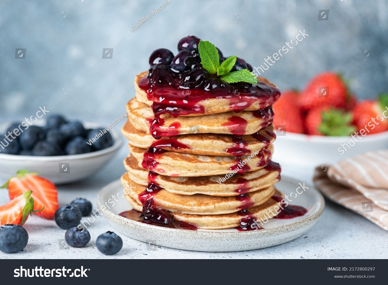 Delicious oatmeal pancakes with berry fruit blueberry strawberry jam dessert topping. Blue background #2172800297