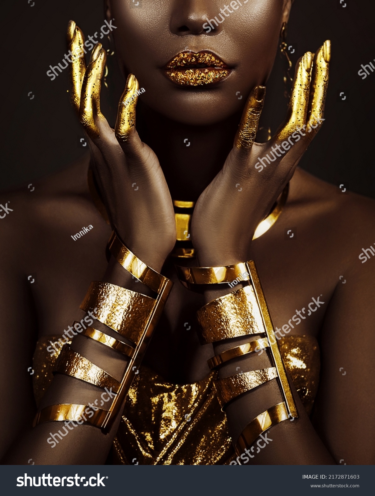 art fantasy portrait african american woman. female hands close-up, fingers in golden paint. Girl queen Cleopatra style. greek gold bracelets. Creative metallic professional makeup lips diamonds gloss #2172871603