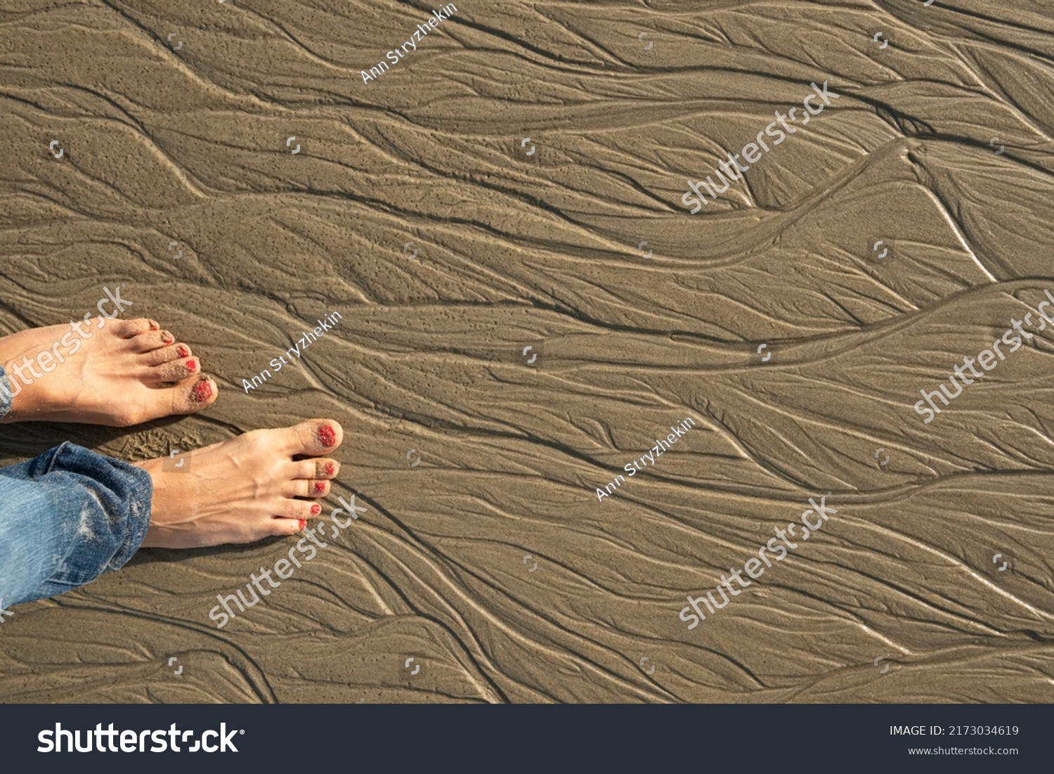 Bare feet in the sand on the beach sand. Patterns on the sand from the water at low tide. #2173034619