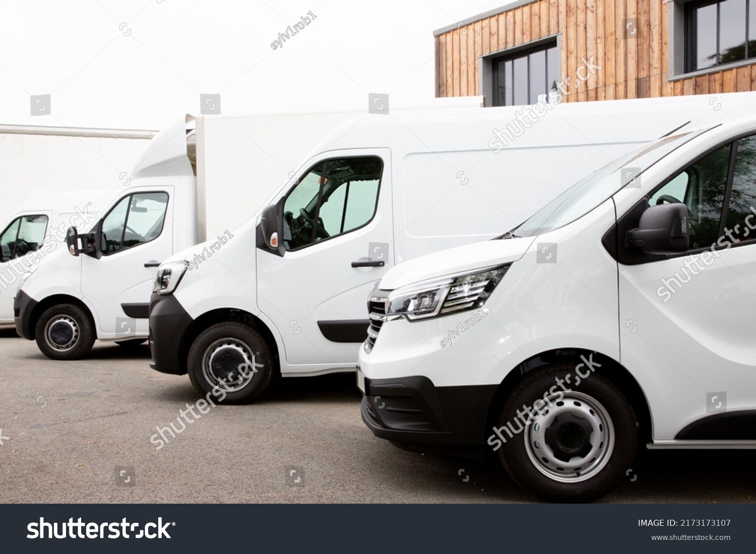 Several cars vans trucks parked in parking lot for rent delivery white vans in service van truck front of entrance of warehouse distribution logistic society #2173173107