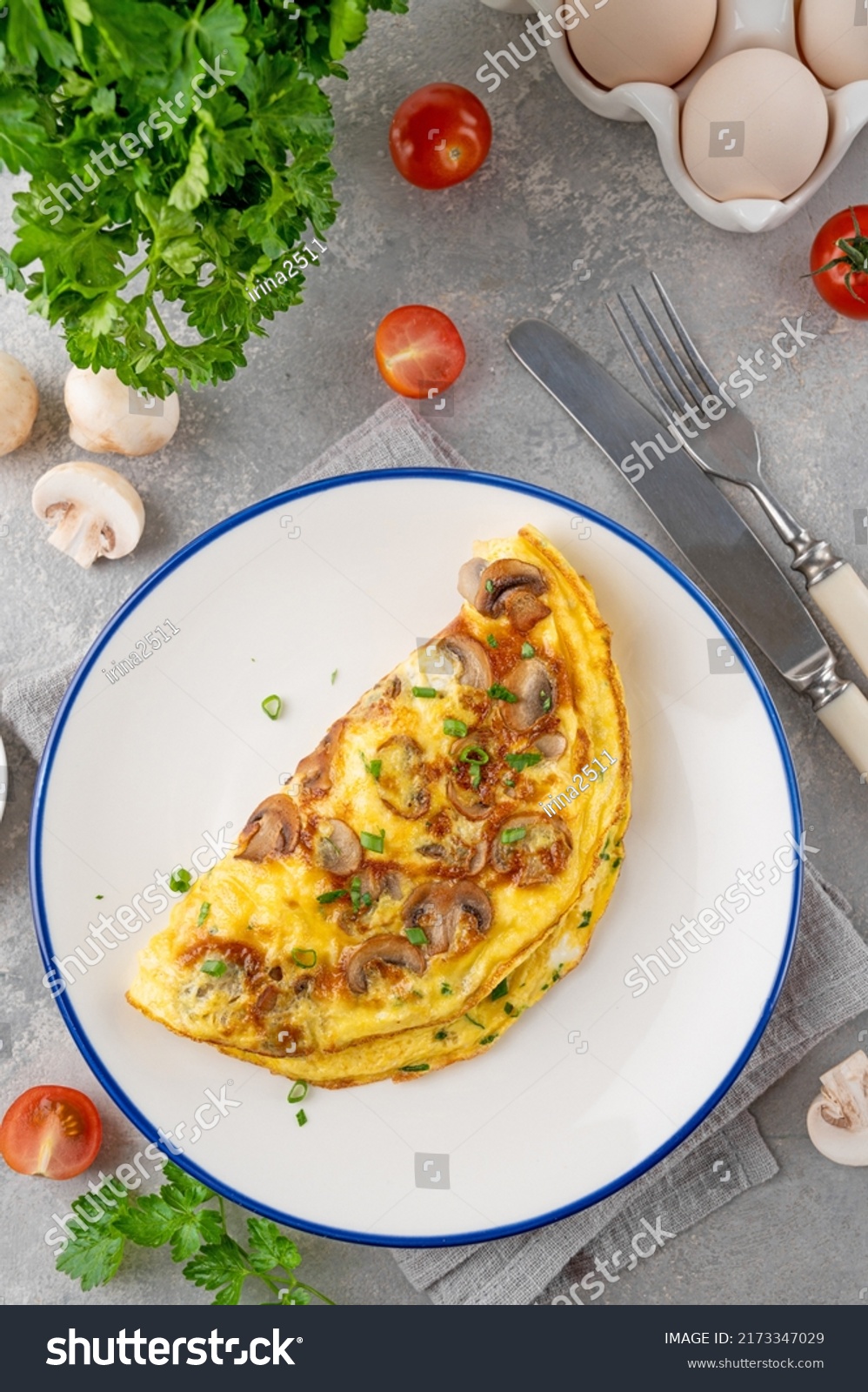 Omelet with fried mushrooms and fresh herbs in a plate on a concrete background. Delicious healthy breakfast. Top view. Copy space #2173347029