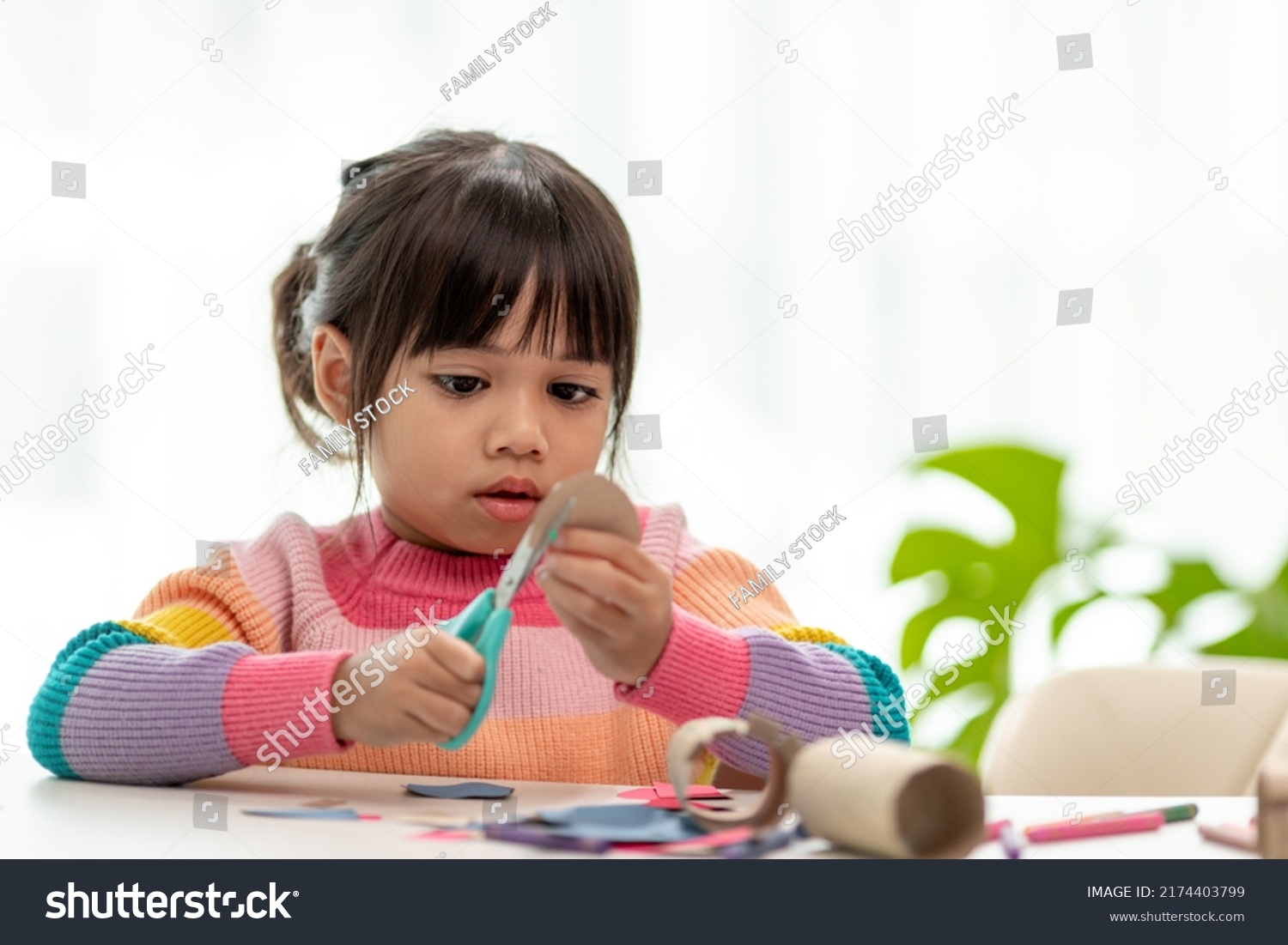 Portrait of a little asian girl cutting a paper in activities on DIY class at School.Scissors cut paper. #2174403799