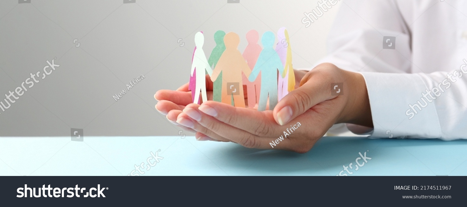 Woman holding paper human figures at table, closeup. Diversity and Inclusion concept #2174511967