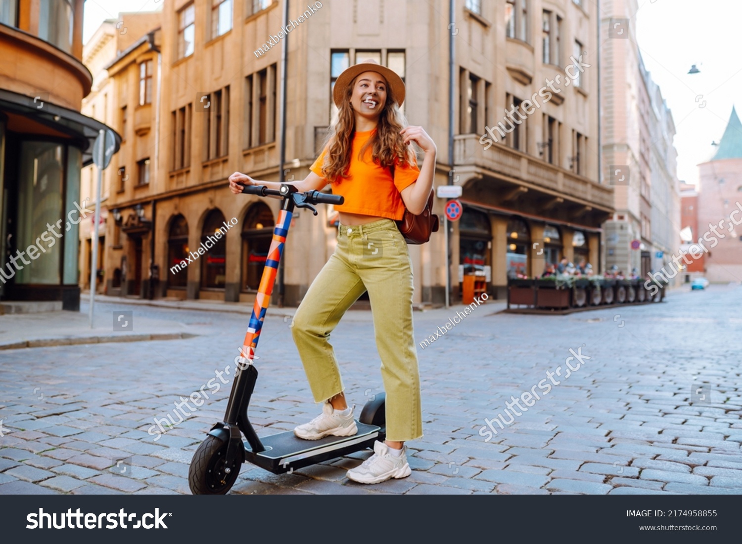 Young beautiful woman riding an electric scooter in the summer on the street.  Active life. Ecological transportation concept. #2174958855