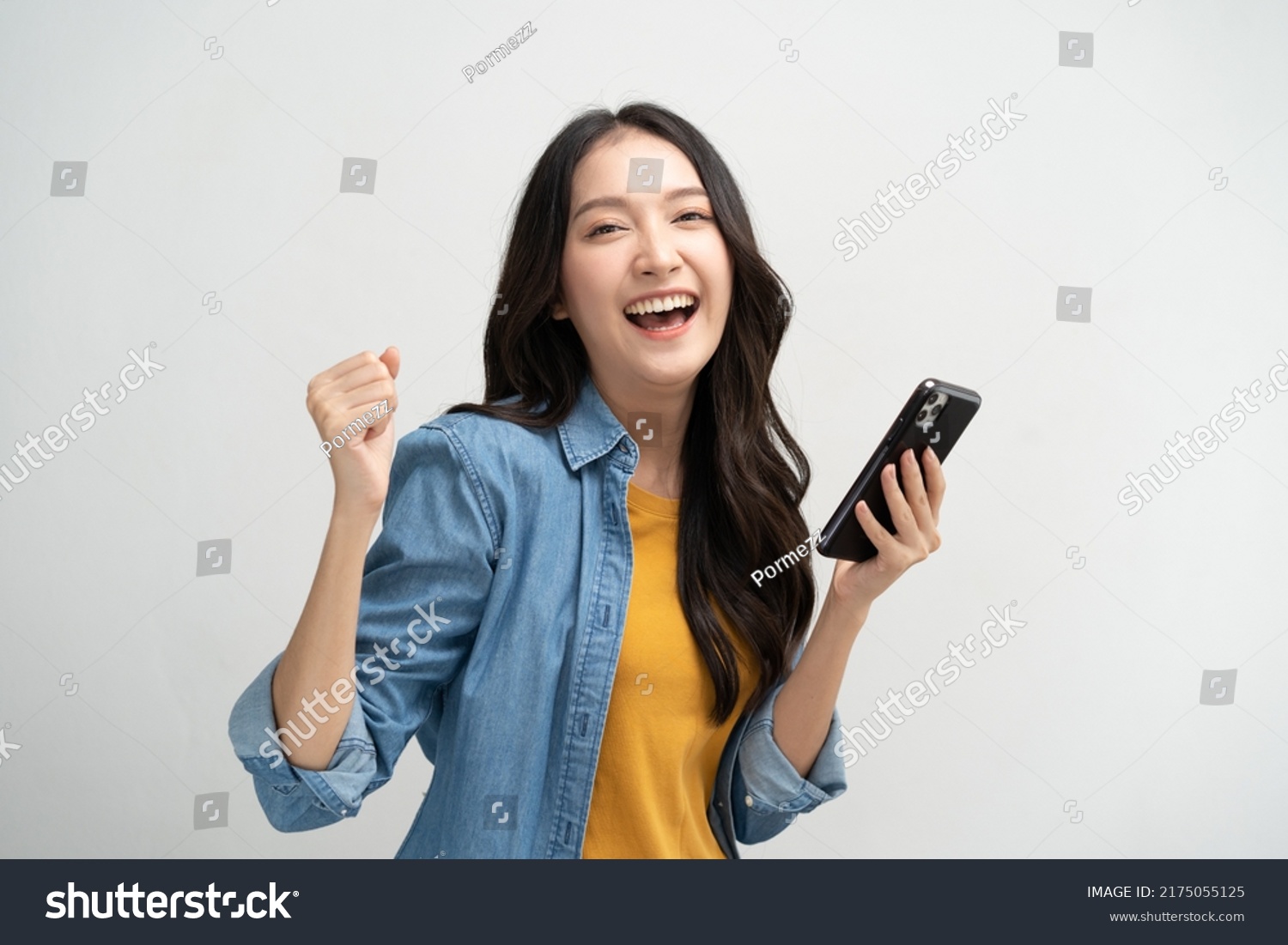 Happy Asian woman holding a smartphone and winning the prize. #2175055125