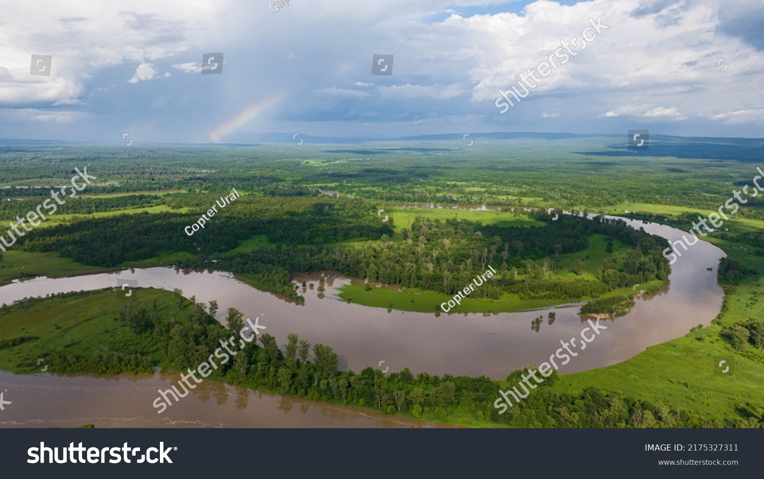 Flooded river floodplain with field and forest in wild lanscape. High altitude wide drone shot flooded area at spring time cloudy day #2175327311