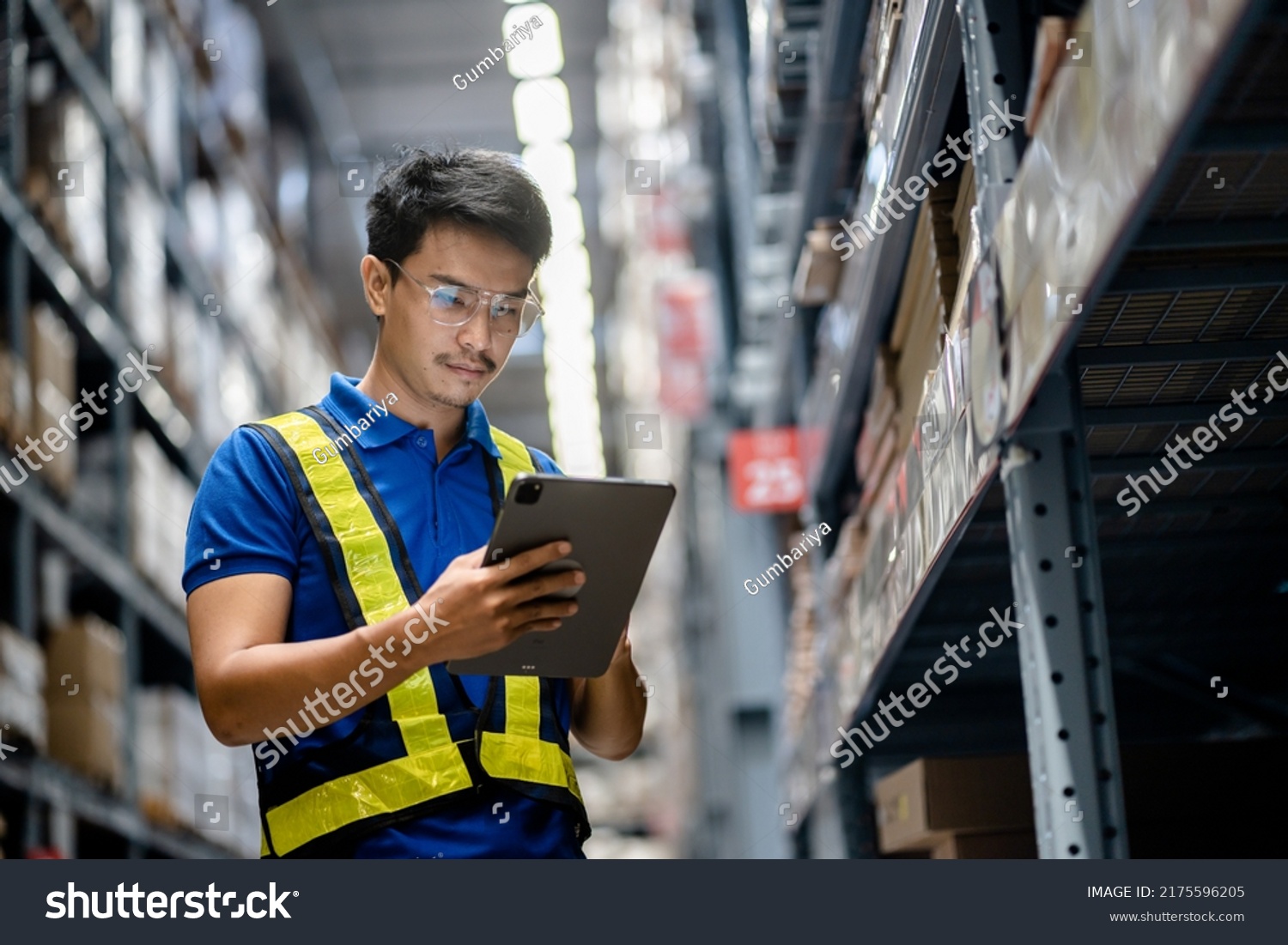 Warehouse Worker in safety suite using digital tablets to check the stock inventory in large warehouses, a Smart warehouse management system, supply chain and logistic network technology concept. #2175596205