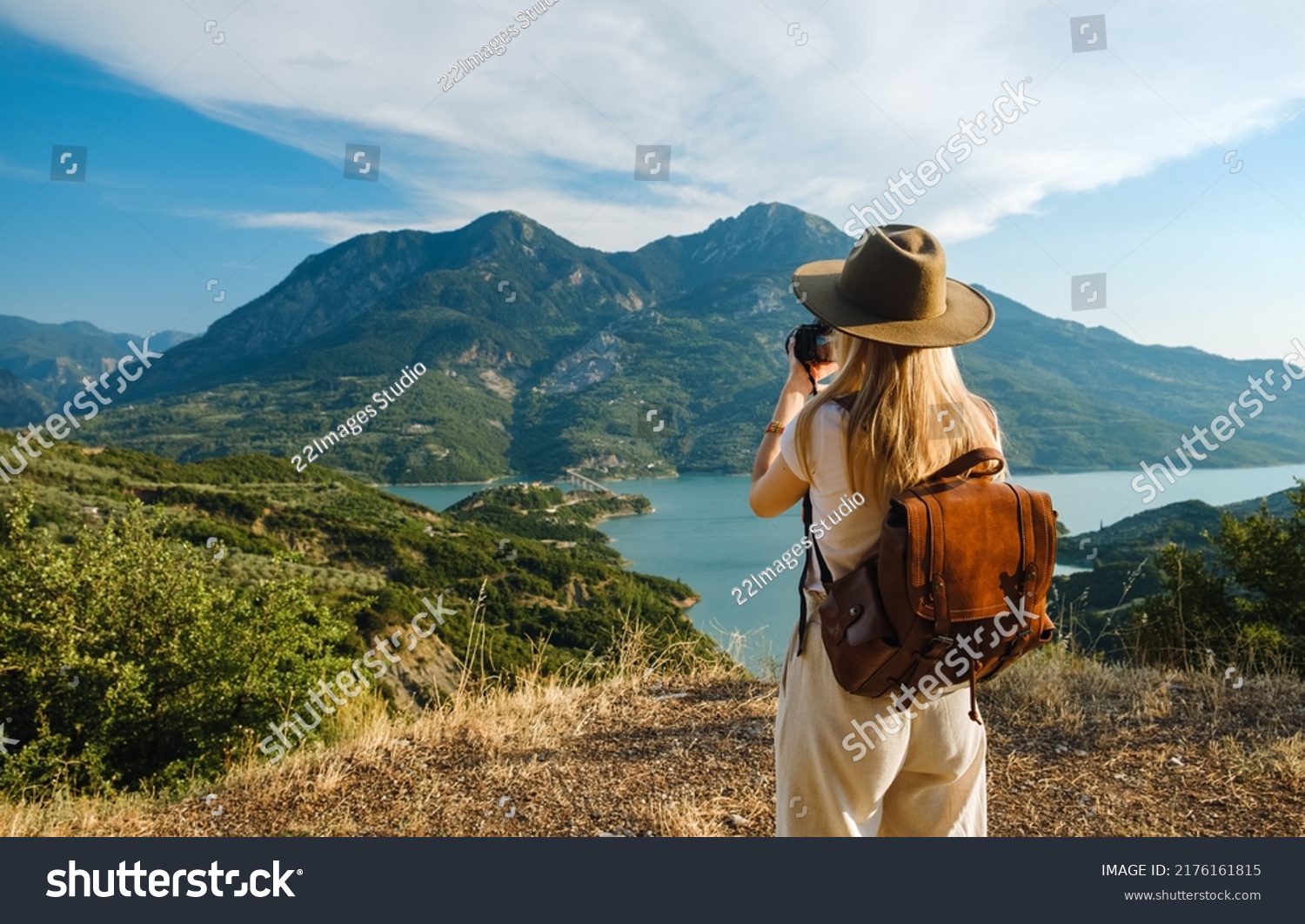 Woman photographer with big backpack taking photo of mountains and blue lake. Travel and hobby concept #2176161815