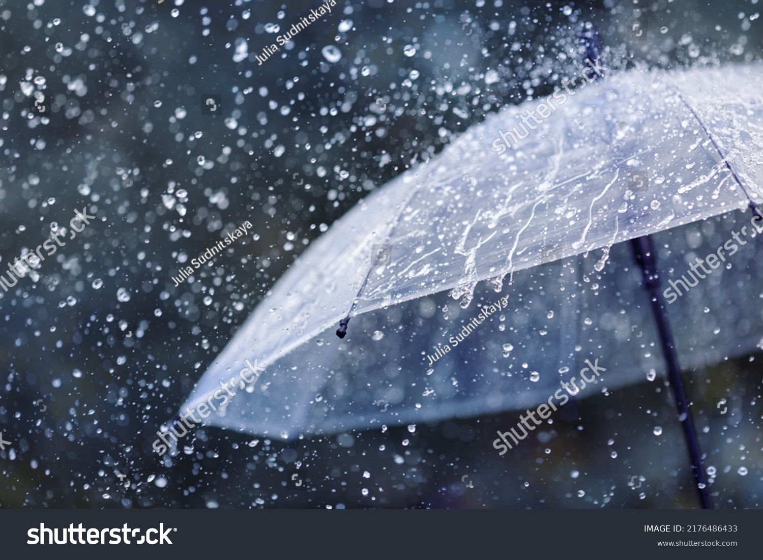 Transparent umbrella under heavy rain against water drops splash background. Rainy weather concept. #2176486433