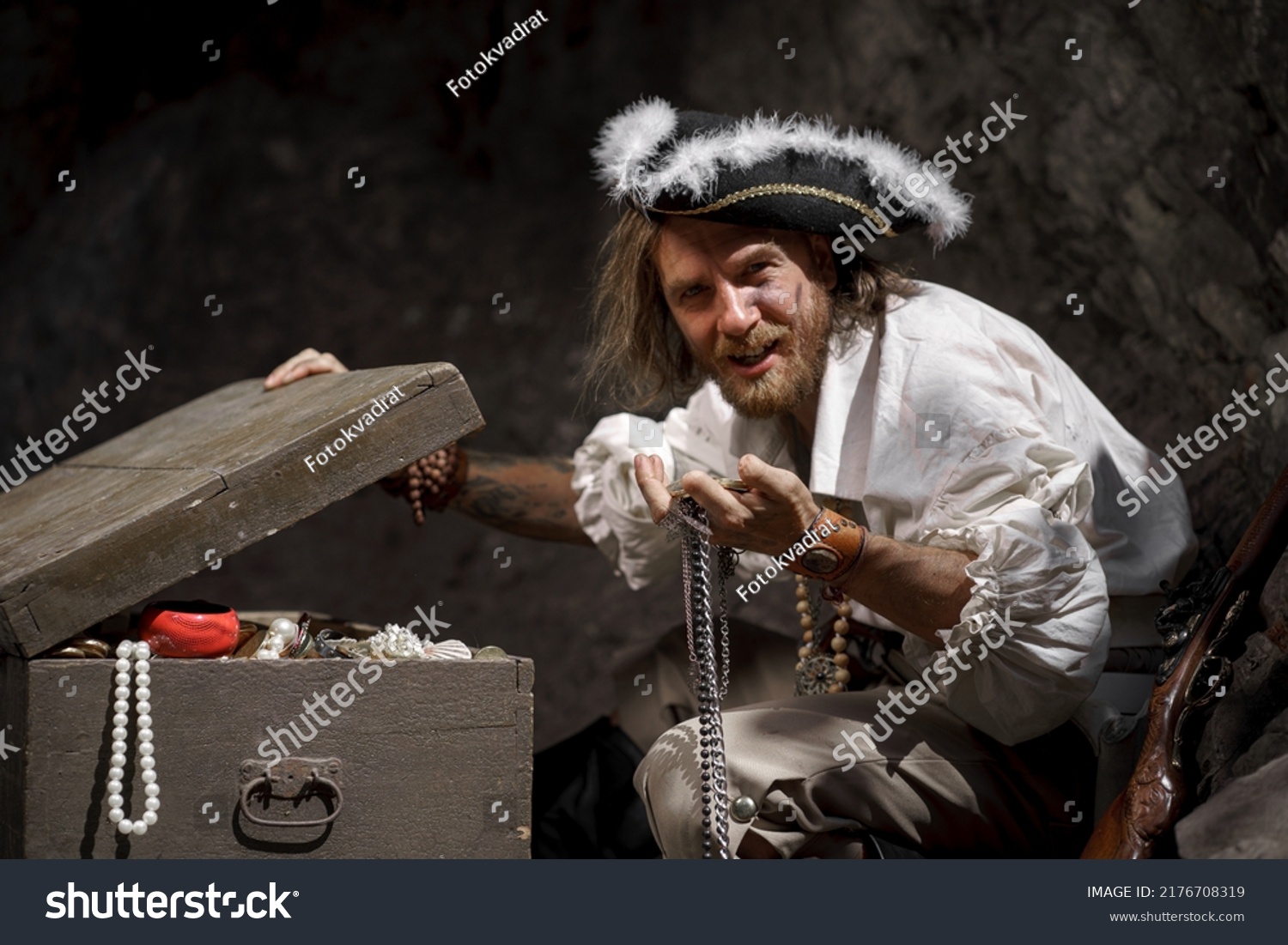 Sea robber captain of pirate ship armed with treasure chest in cave. Concept historical halloween. Filibuster cosplay. #2176708319