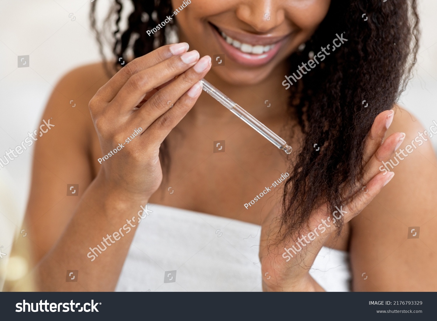 Split Ends Care. Smiling African American Woman Applying Moisturising Oil To Her Curly Hair, Closeup Of Young Black Female Putting Haircare Product With Dropper While Making Beauty Routine At Home #2176793329