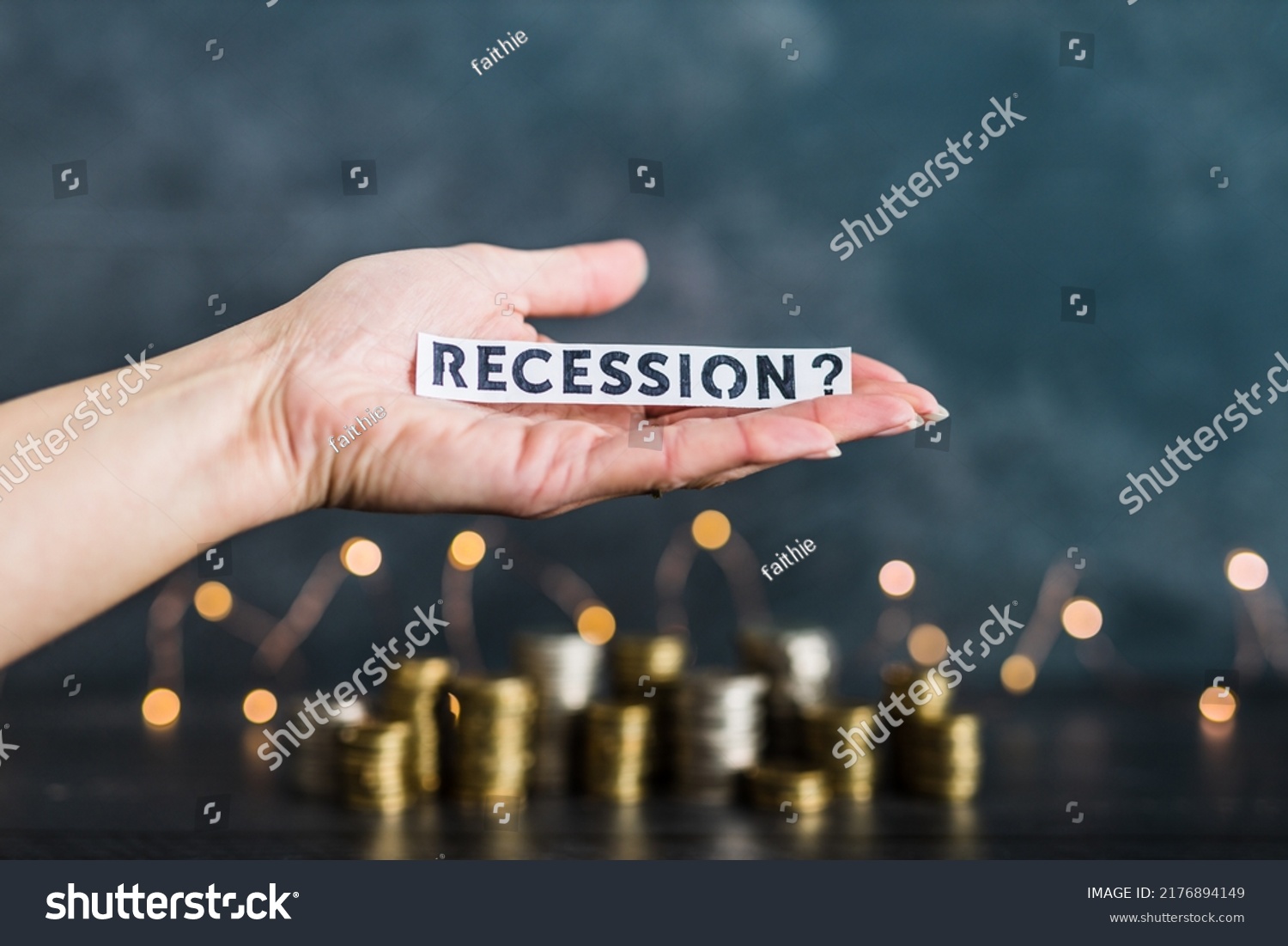 recession and inflation after the Covid-19 pandemic conceptual image, hand holding Recession text in front of stacks of coins with fairy lights in the background #2176894149