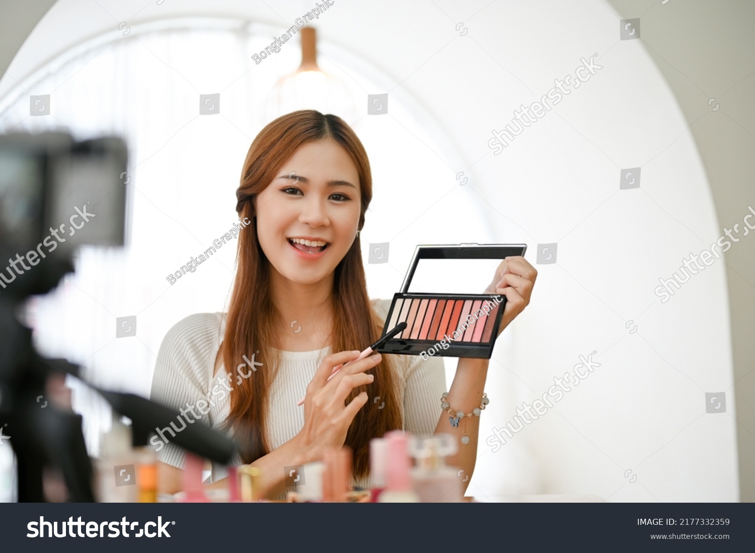 Talented young Asian female beauty blogger or influencer giving advice and reviews after using the eye shadows cosmetic product in live-streaming on social media. #2177332359