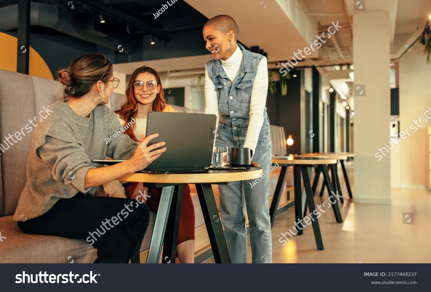 Group of young businesswomen working together in an office lobby. Three happy businesswomen having a discussion in a modern co-working space. Young female entrepreneurs collaborating on a new project. #2177468237