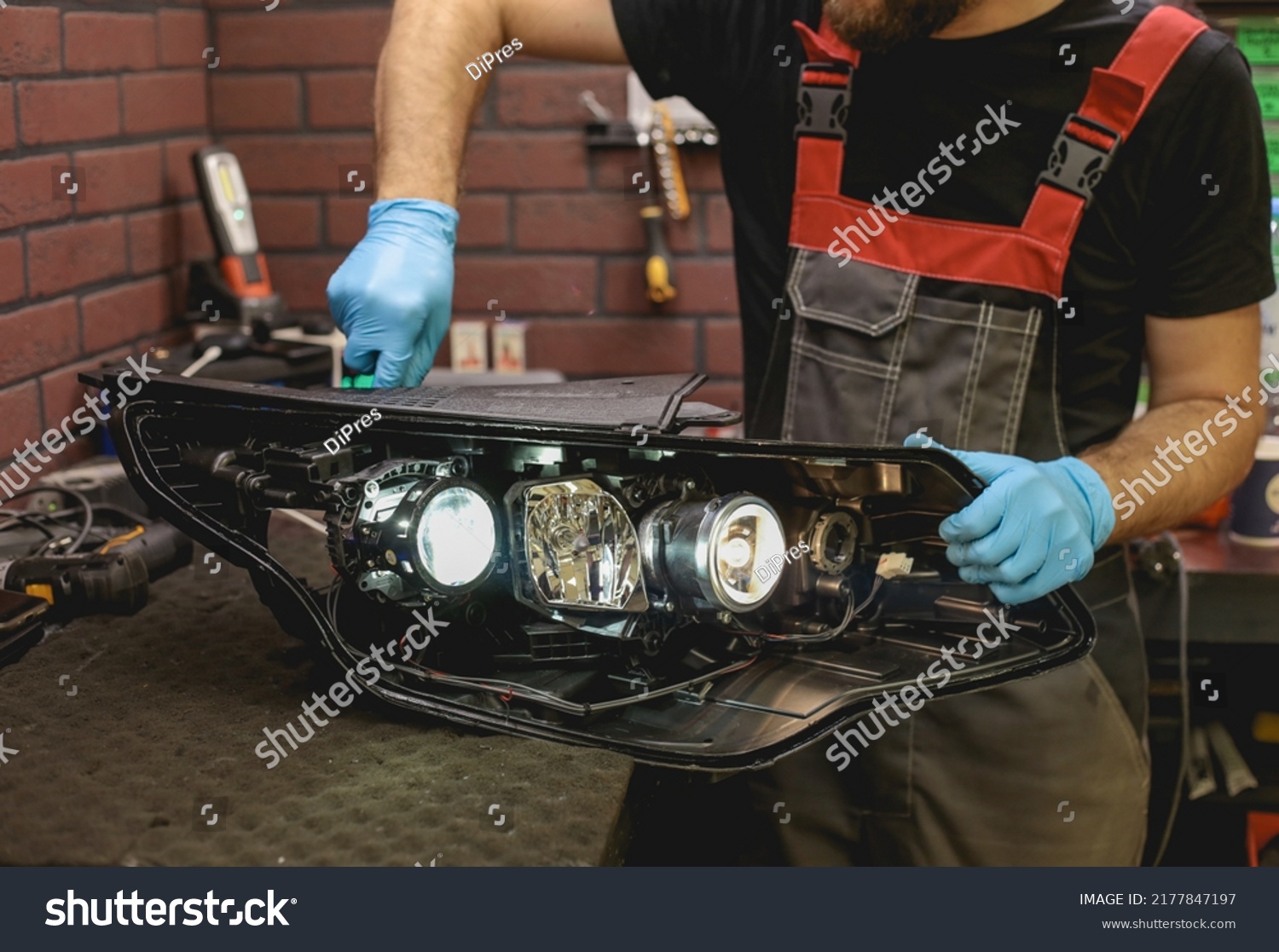 Car headlight in repair close-up. The car mechanic installs the lens in the headlight housing. The concept of a car service.Installation of LED lenses in the headlight. LED lens.Restoration of optics. #2177847197