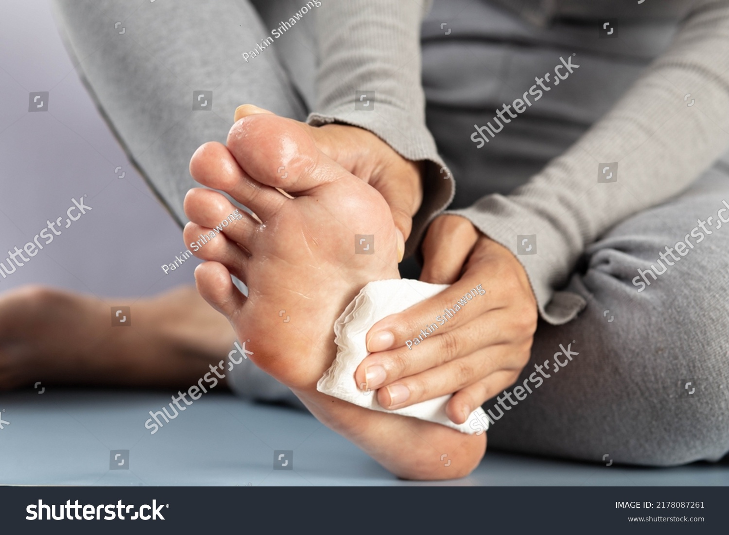 Hyperhidrosis, The woman wipes her feet after they have been excessively perspiring. #2178087261