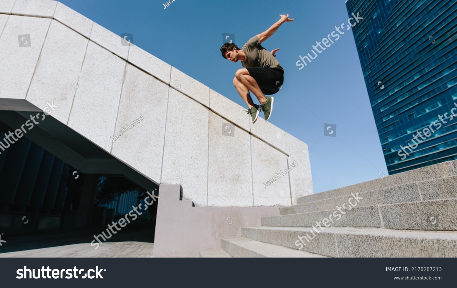 Young man jumping high over steps outdoors. Fit male free runner jumping over stairs in urban space. #2178287213