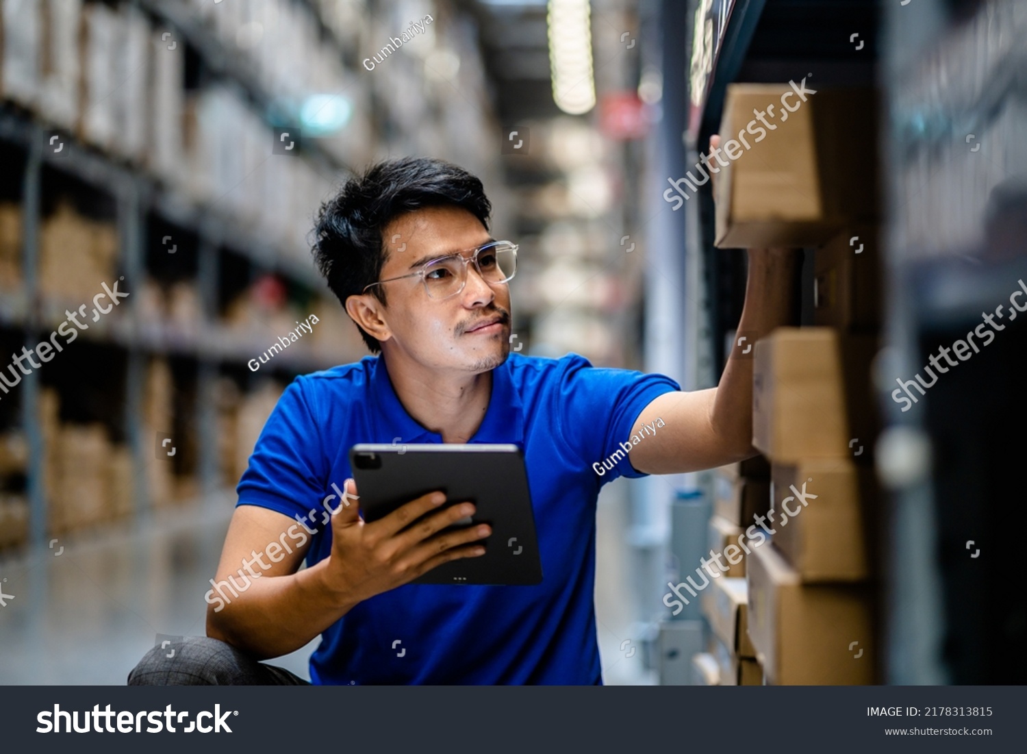 Warehouse Worker in safety suite using digital tablets to check the stock inventory in large warehouses, a Smart warehouse management system, supply chain and logistic network technology concept. #2178313815