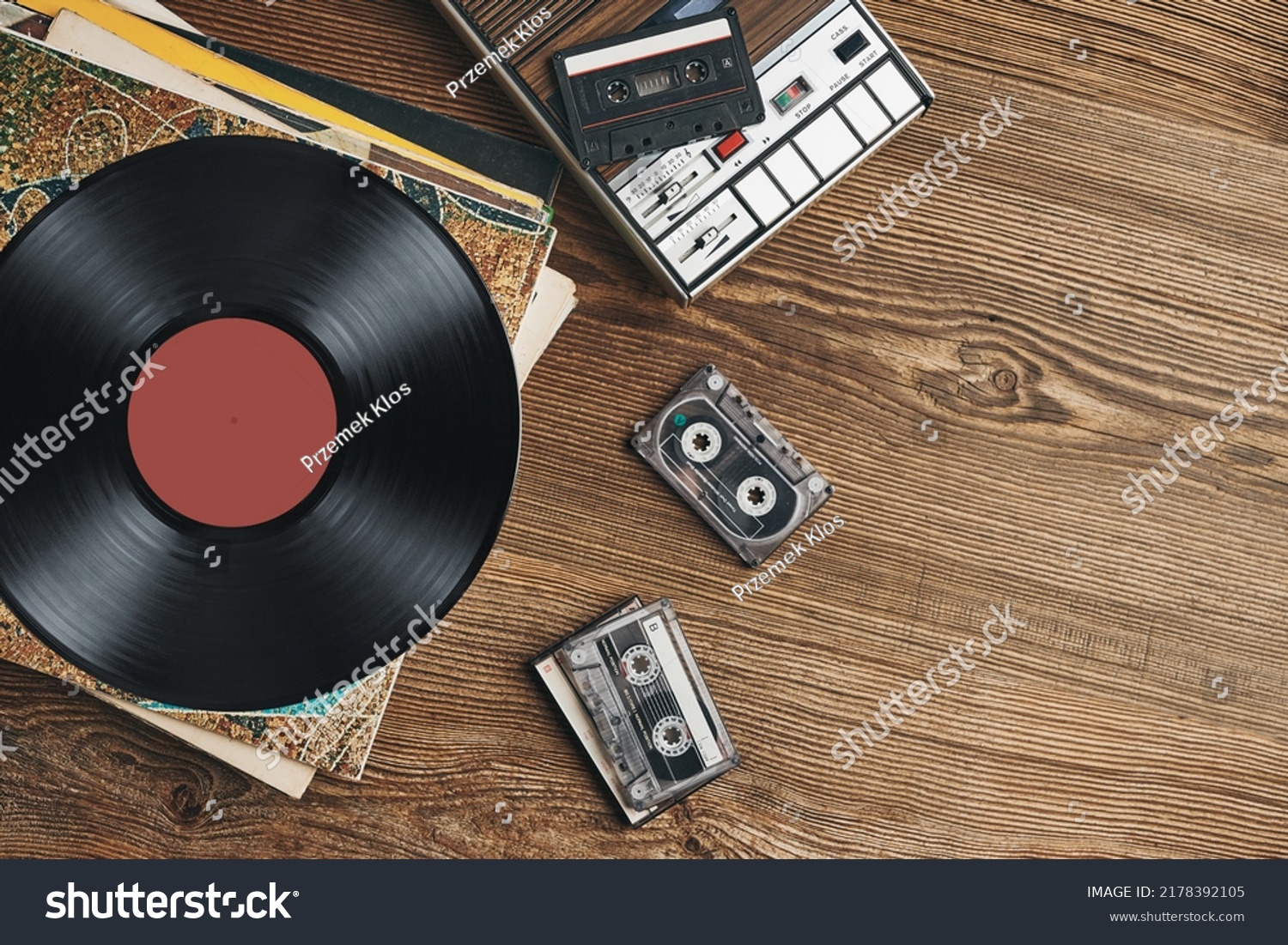 Vinyl records, cassette tapes and cassette recorder on wooden table. Retro music style. 80s music party. Vintage style. Analog equipment. Stereo sound. Back to the past #2178392105