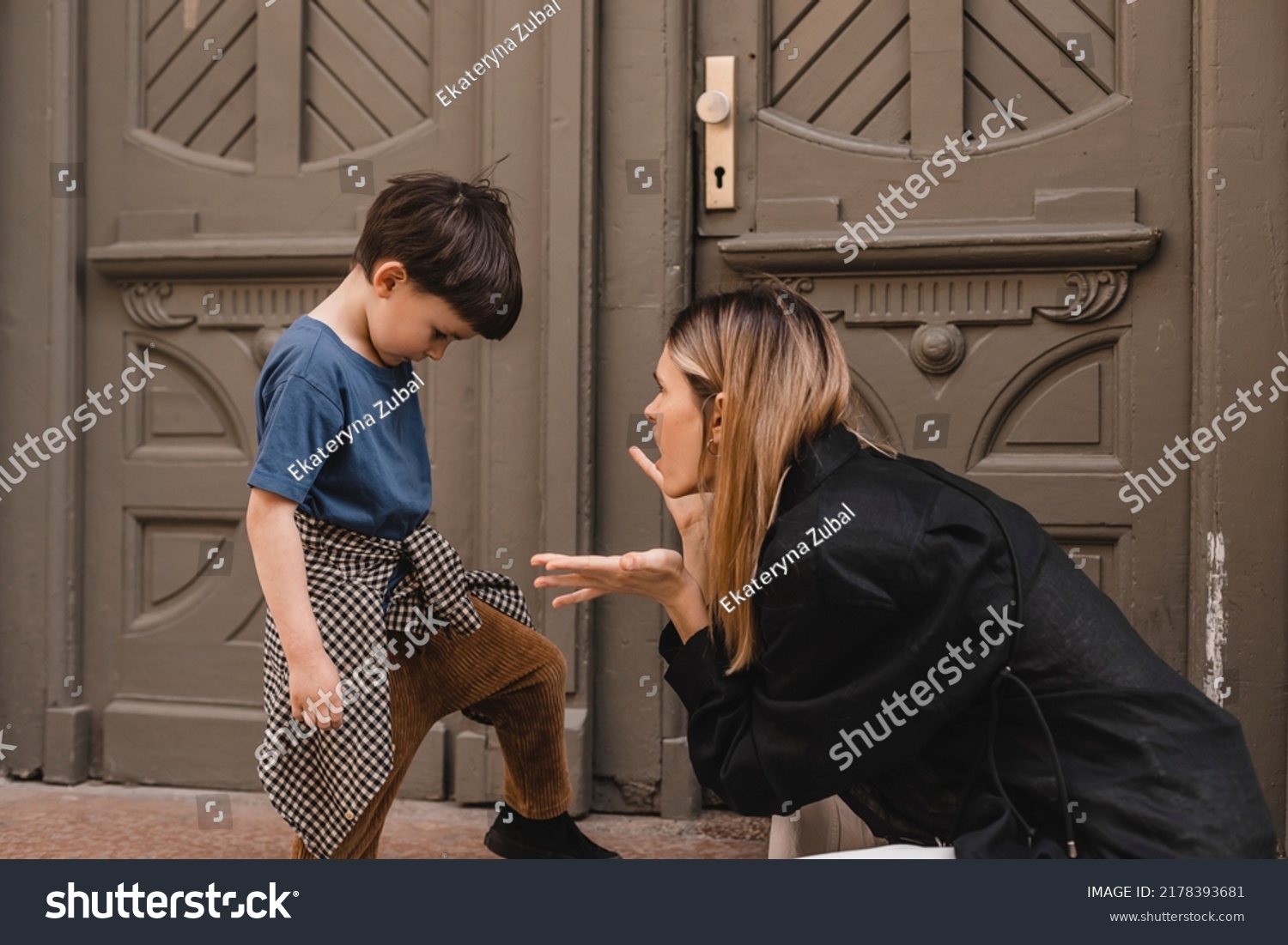 Mother scolds her son on the street. A child cries, a woman shakes her finger because of the boy bad behavior, while walking to home. Rule of conduct. Woman sitting, boy cover his face and cry. #2178393681