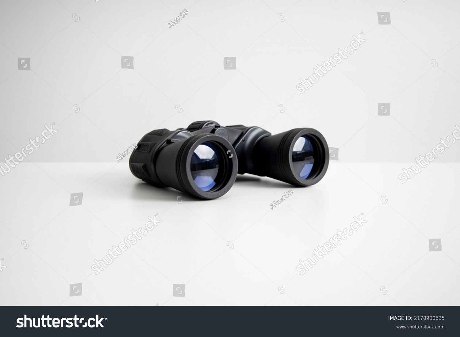 Black binoculars lying on a white background. Side view. #2178900635