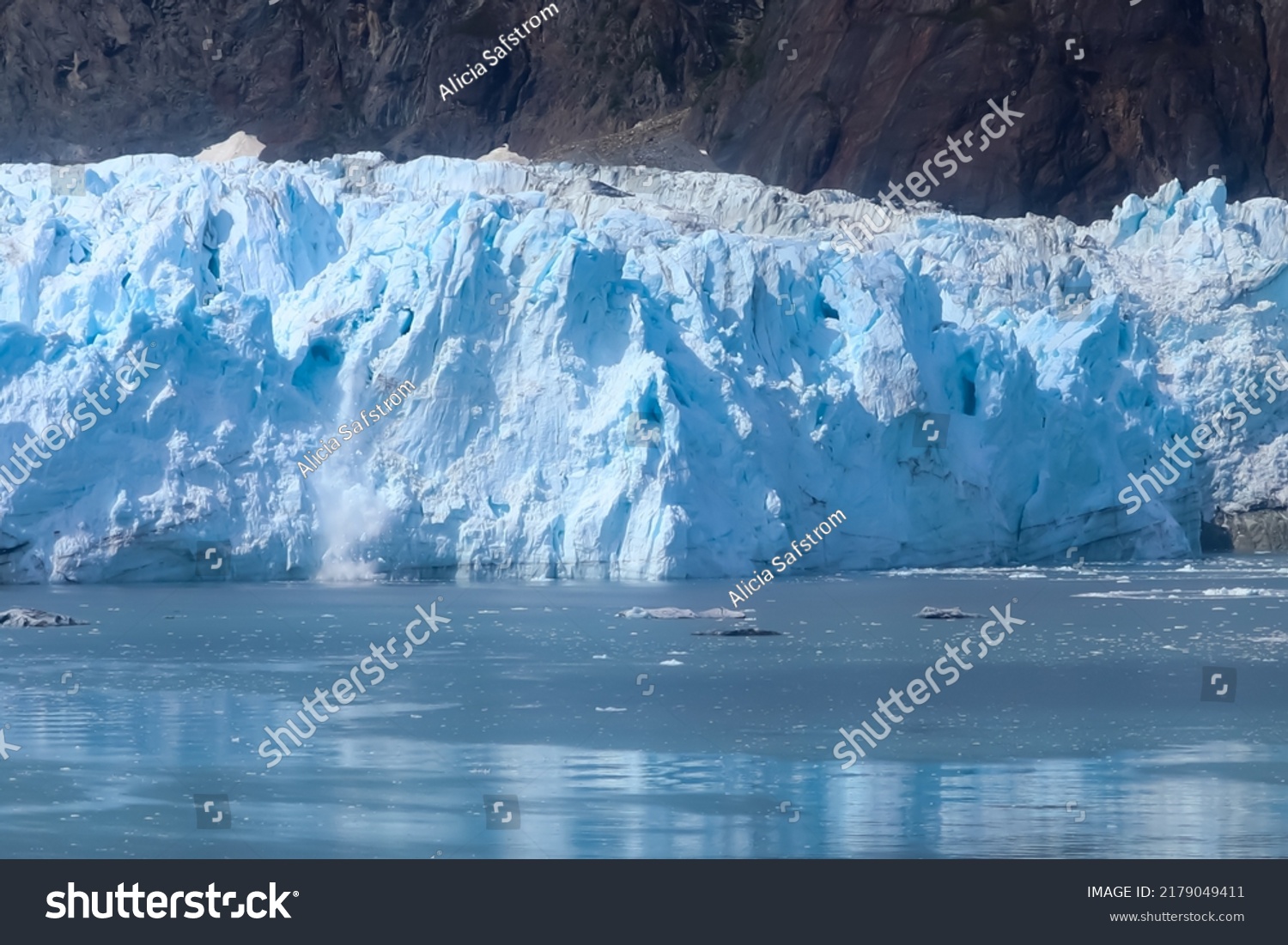 Chunks of ice fall off the face of a glacier into the sea #2179049411