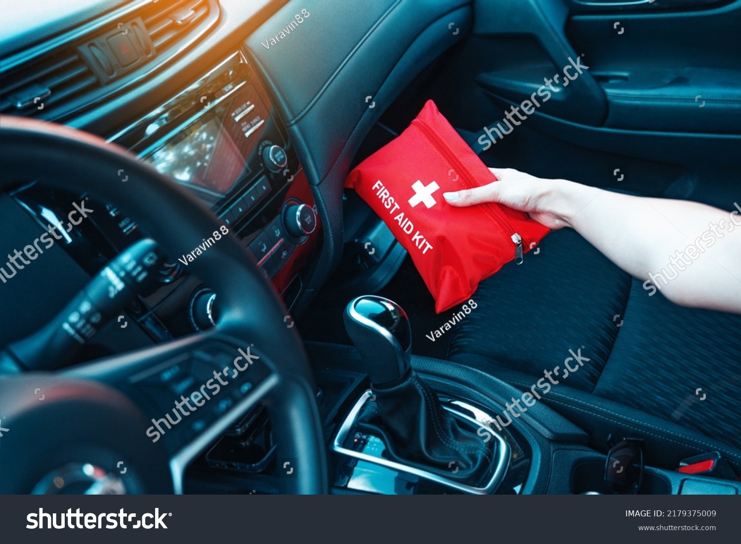 Female hand taking red first aid kit from the car glove box. A well-equipped car for road trips concept. #2179375009