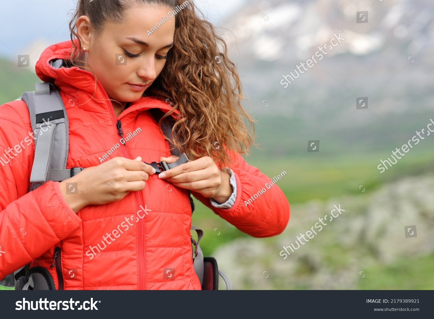 Hiker in red fastening backpack strap in the mountain ready to walk #2179389921