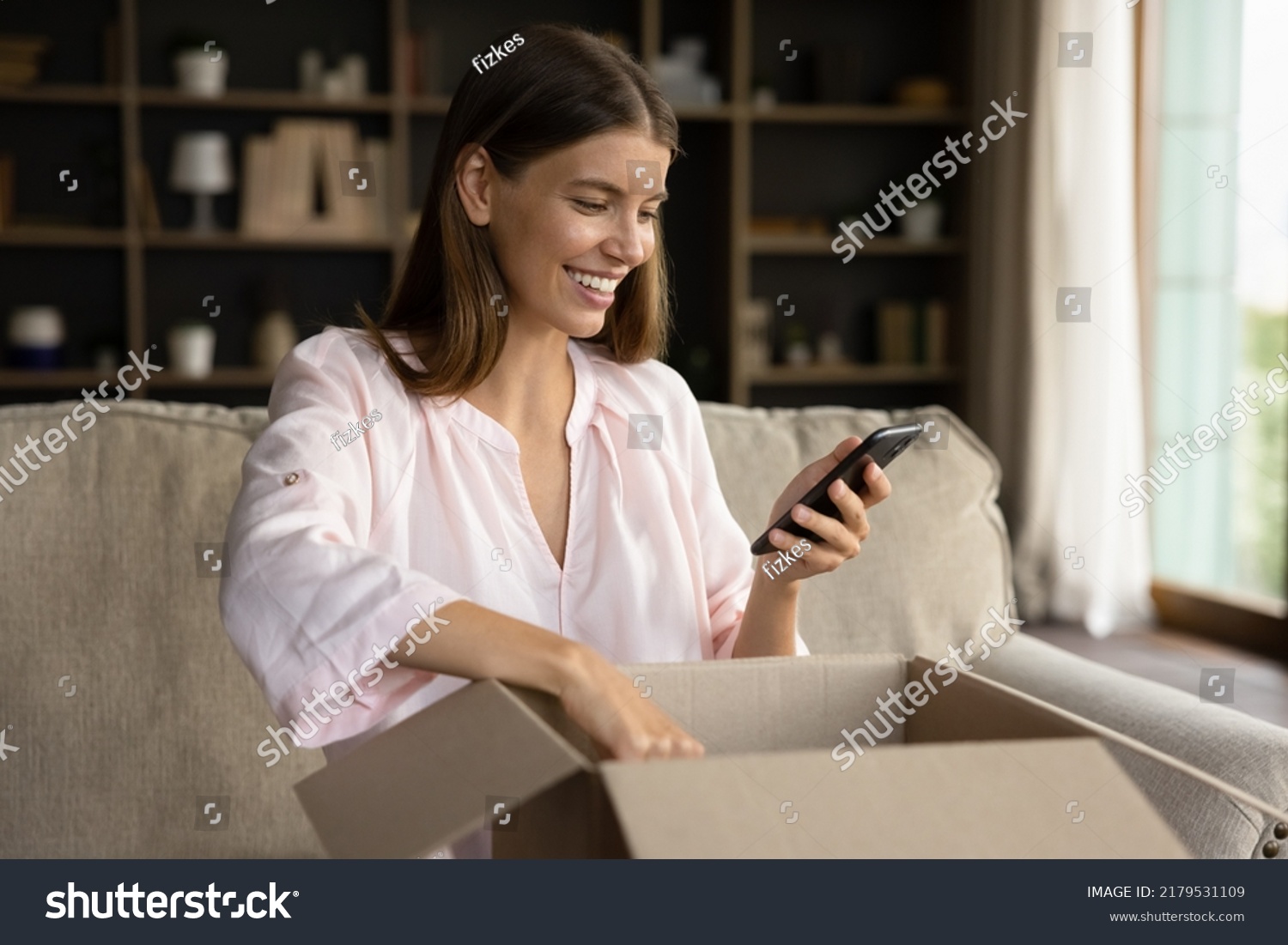 Happy woman unbox parcel box, check ordered items in phone use retail ecommerce application, leave positive feedback to customer, feel satisfied with delivered goods, quick delivery services concept #2179531109