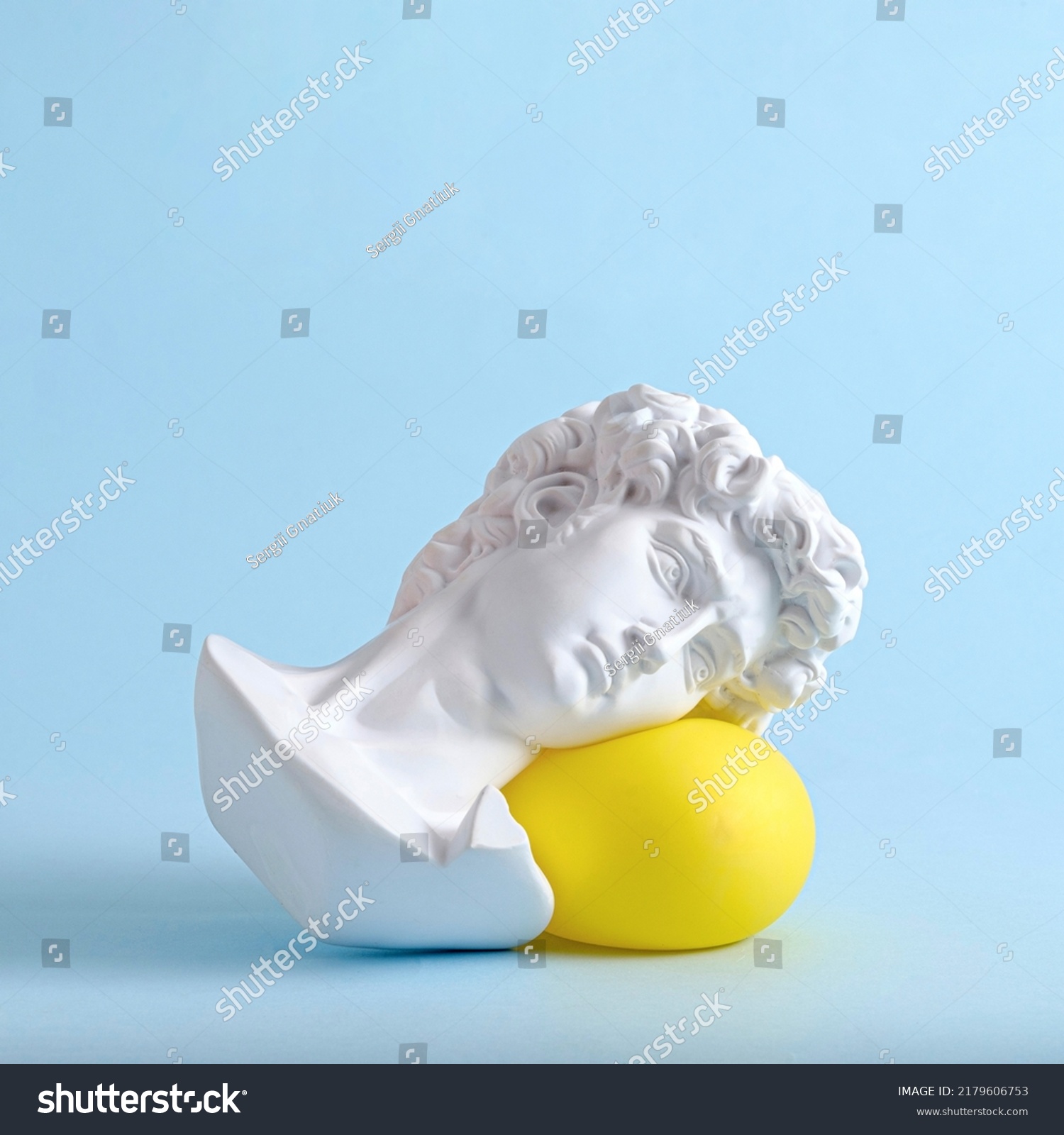 The head and face of David of an antique statue lies on a yellow balloon as a minimal trend concept of vaporwave surreal or sleep. #2179606753