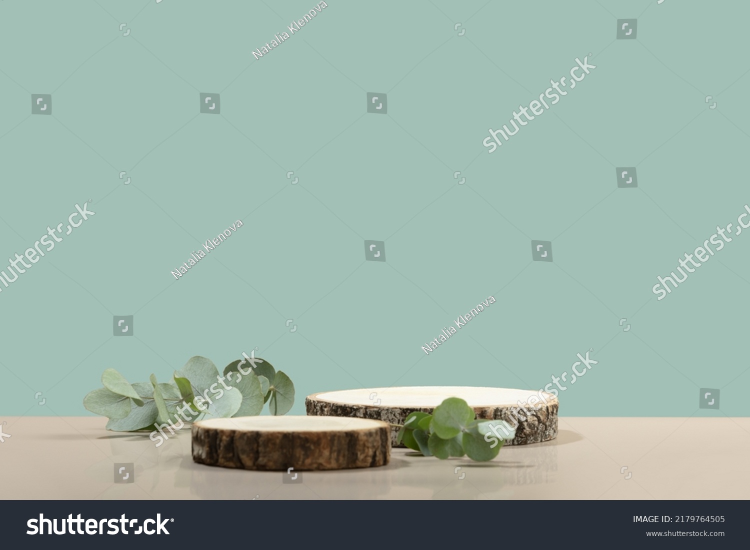 Two cosmetic product podiums mockup. Background for presentation of cosmetic. Minimal modern product display on neutral blue background. Wood slice podium and green leaves. Concept scene #2179764505